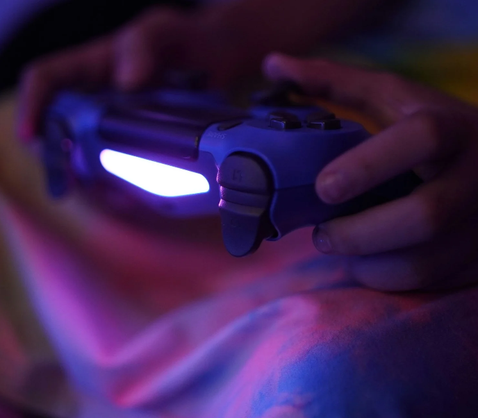 A person holding a game controller that has a light on in the back.