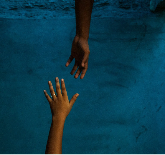 Two hands reaching towards each other underwater.