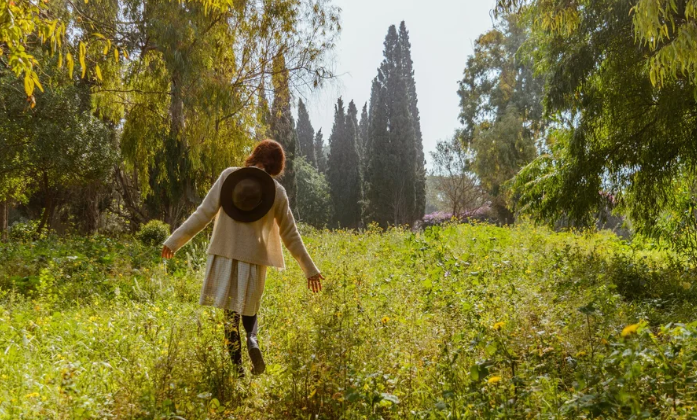 A woman walking through tall flowers and grass