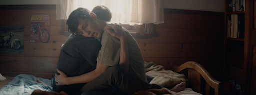 Two boys hugging in a room.
