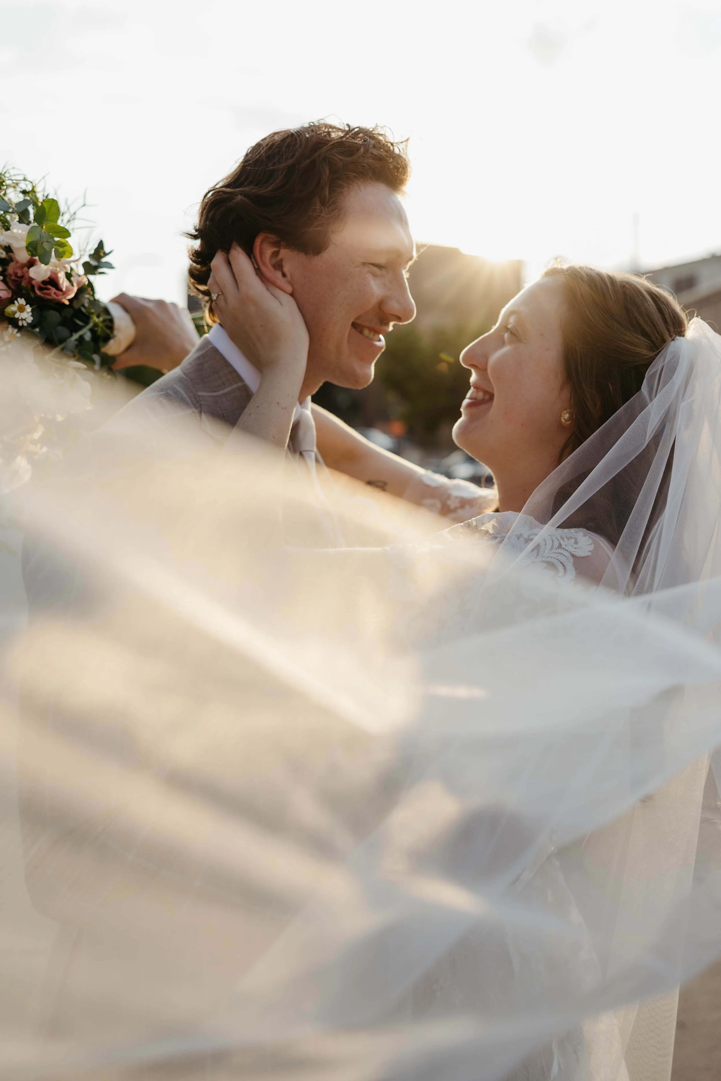 Couple smiling at each other during sunset portraits at Mosaic wedding venue in downtown Sioux Falls photographed by Jenna Heckel Photography. 