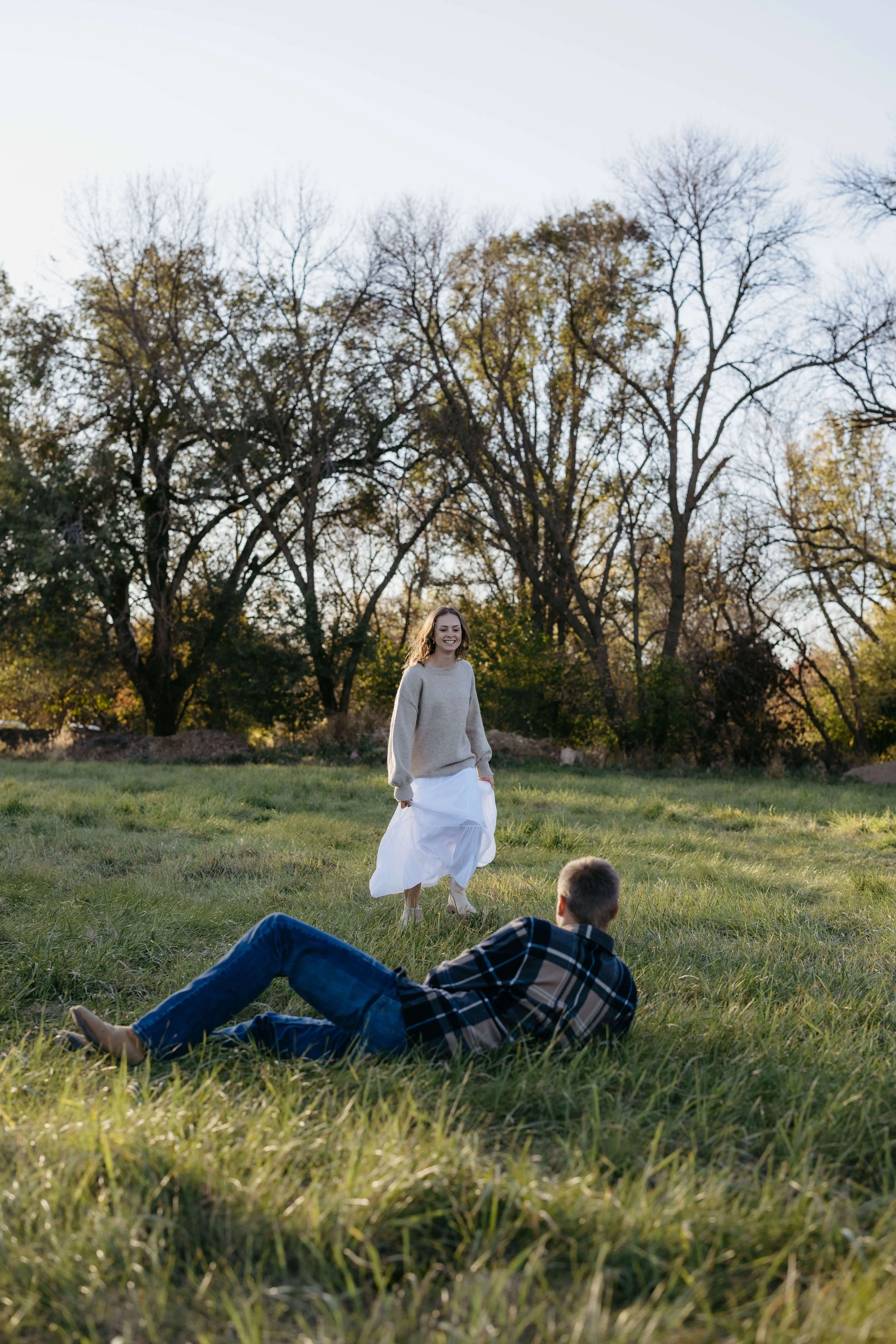 Couple having fun and rolling in the grass during engagement session in Sioux Falls with Jenna Heckel Photography.