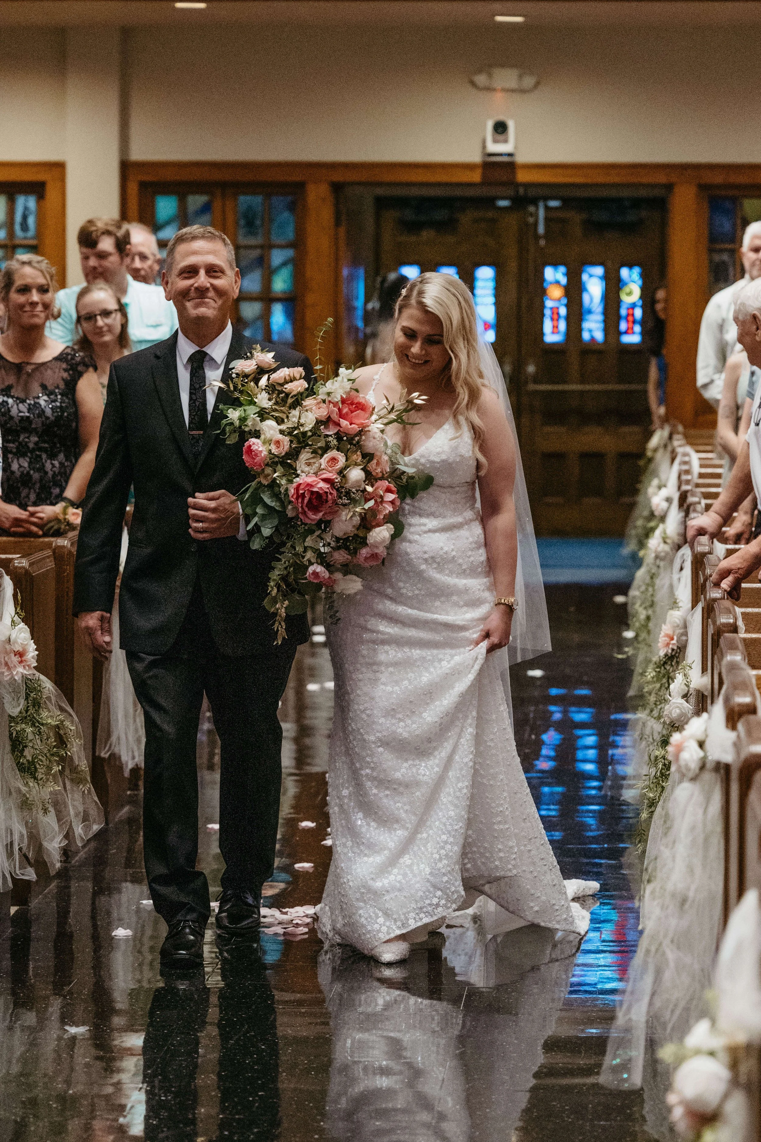 Bride one her wedding day being walked down the aisle by her father at first Lutheran church in downtown Sioux Falls