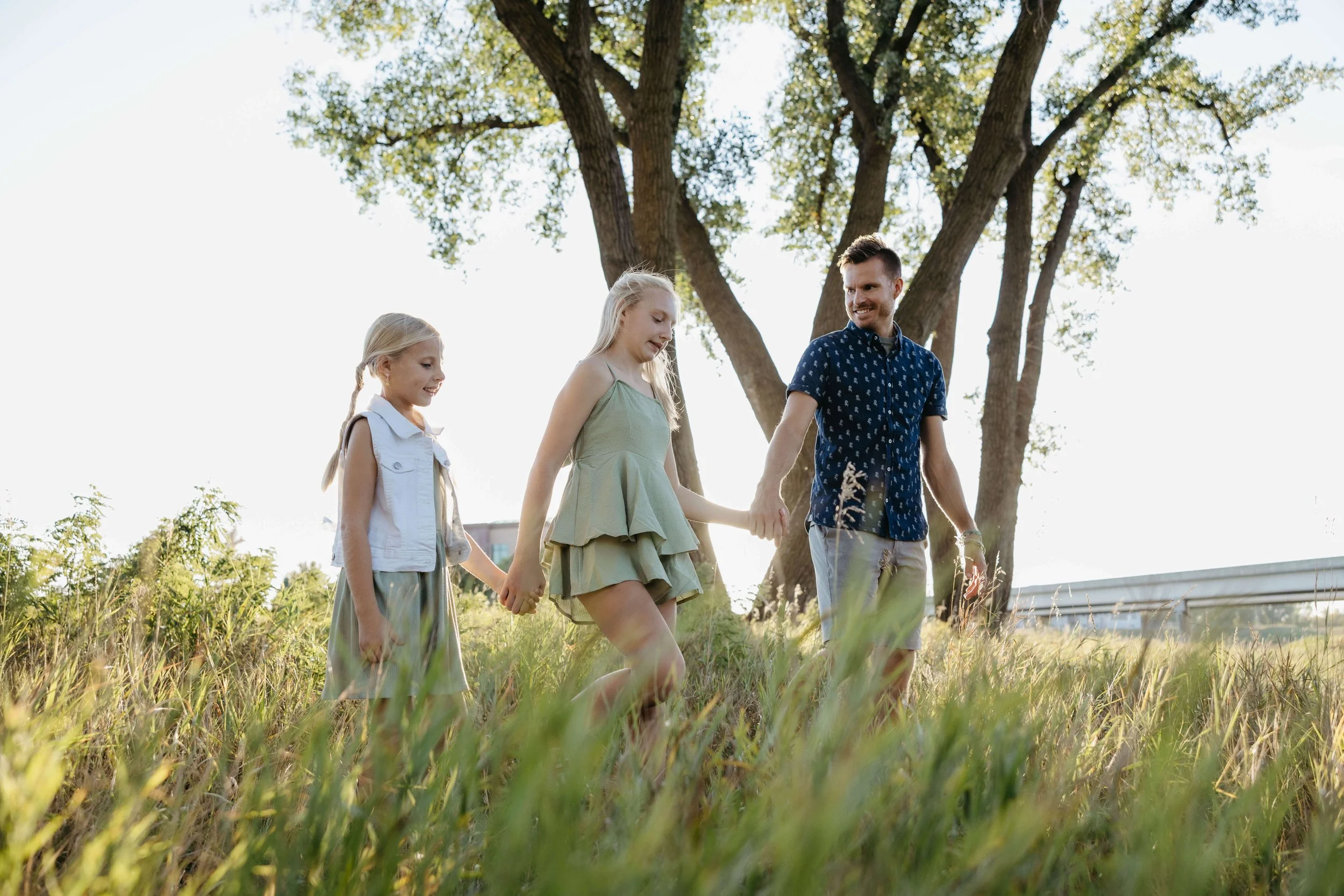 Father and daughters during family photos in Sioux Falls at sunset during the summer. Photographed by Jenna Heckel.
