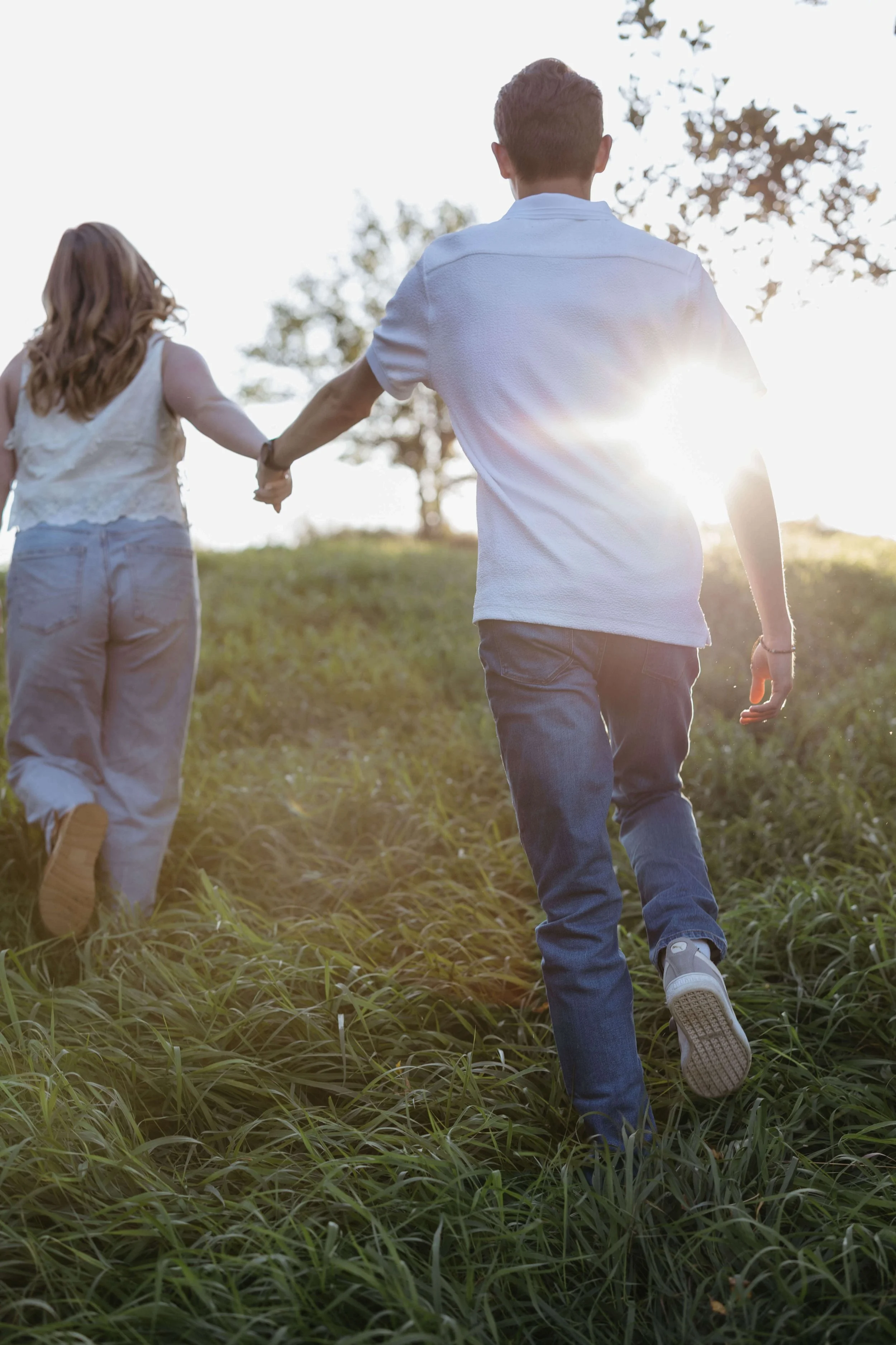 Couple running through the grass at Good Earth State Park taking engagement photos with Jenna Heckel Photography.