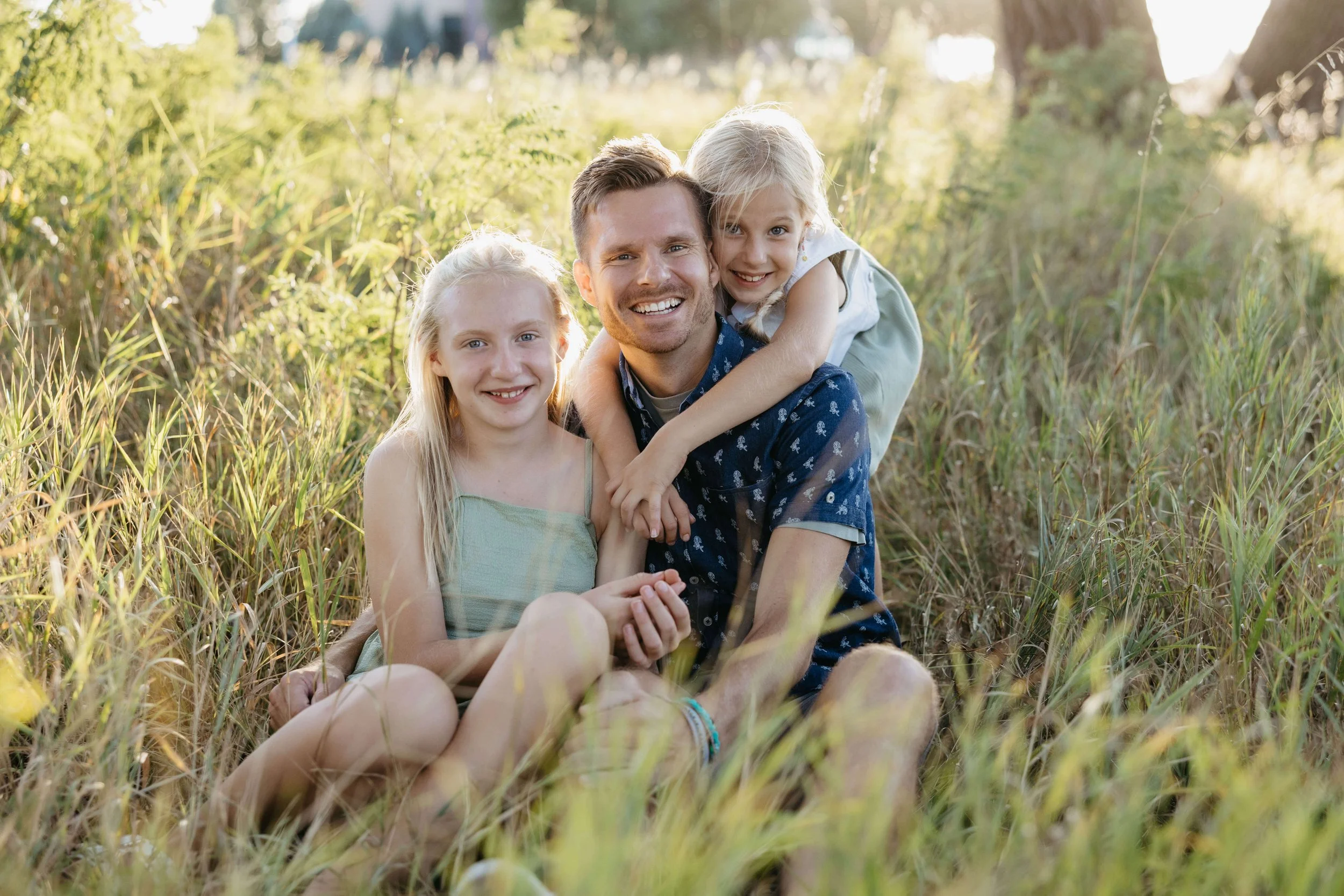 Father and daughters during family photos in Sioux Falls at sunset during the summer. Photographed by Jenna Heckel.