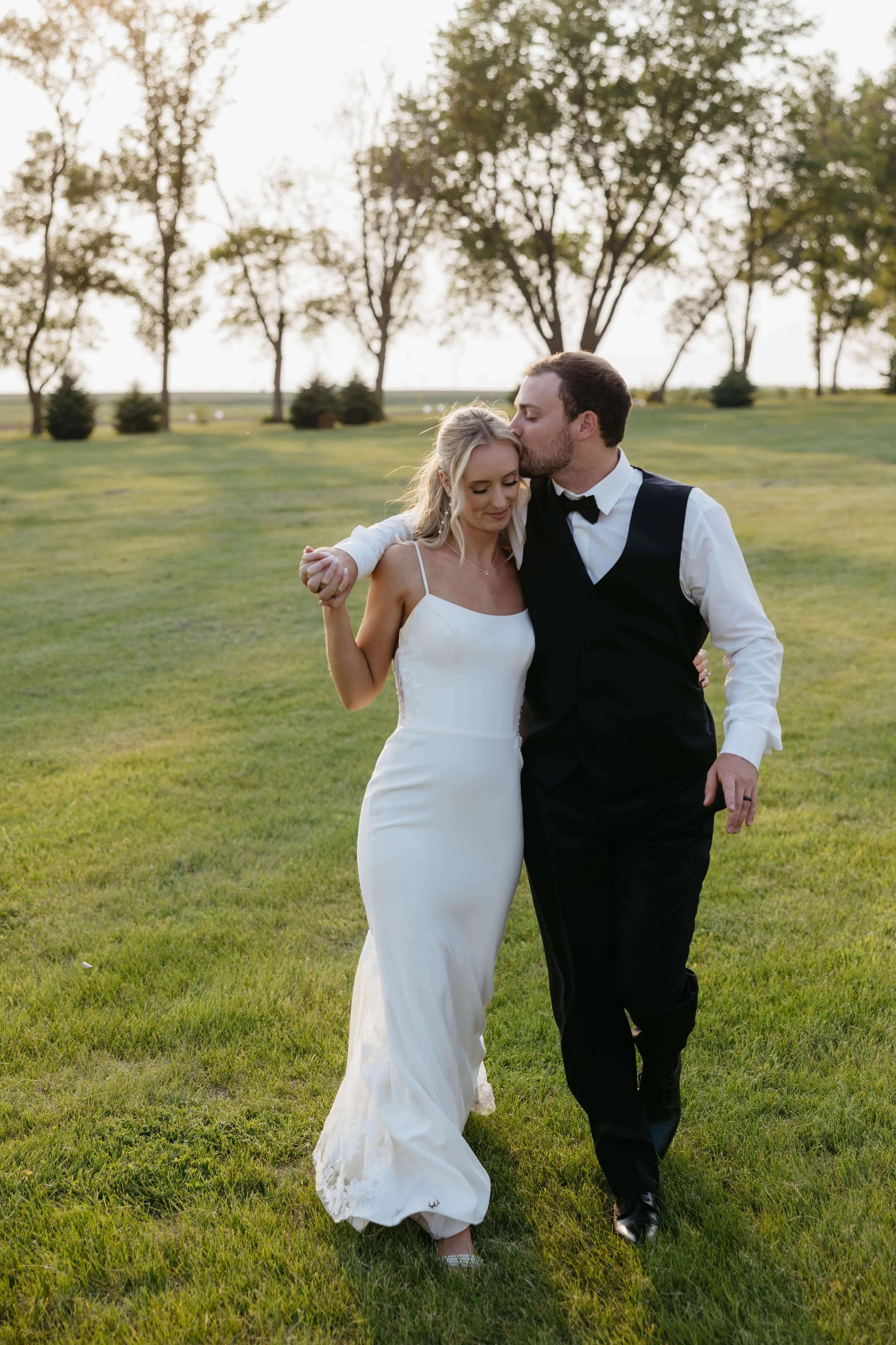 Bride and groom doing sunset portraits in a field in Northwest Iowa during their wedding day photographed by Jenna Heckel.