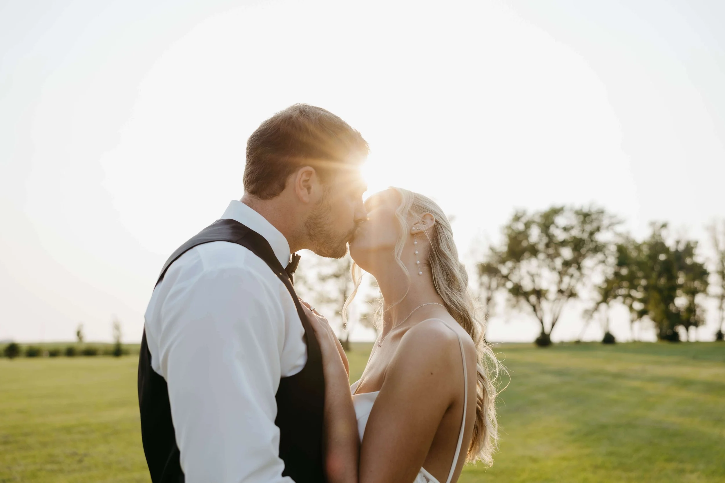 Bride and groom doing sunset portraits in a field in Northwest Iowa during their wedding day photographed by Jenna Heckel.