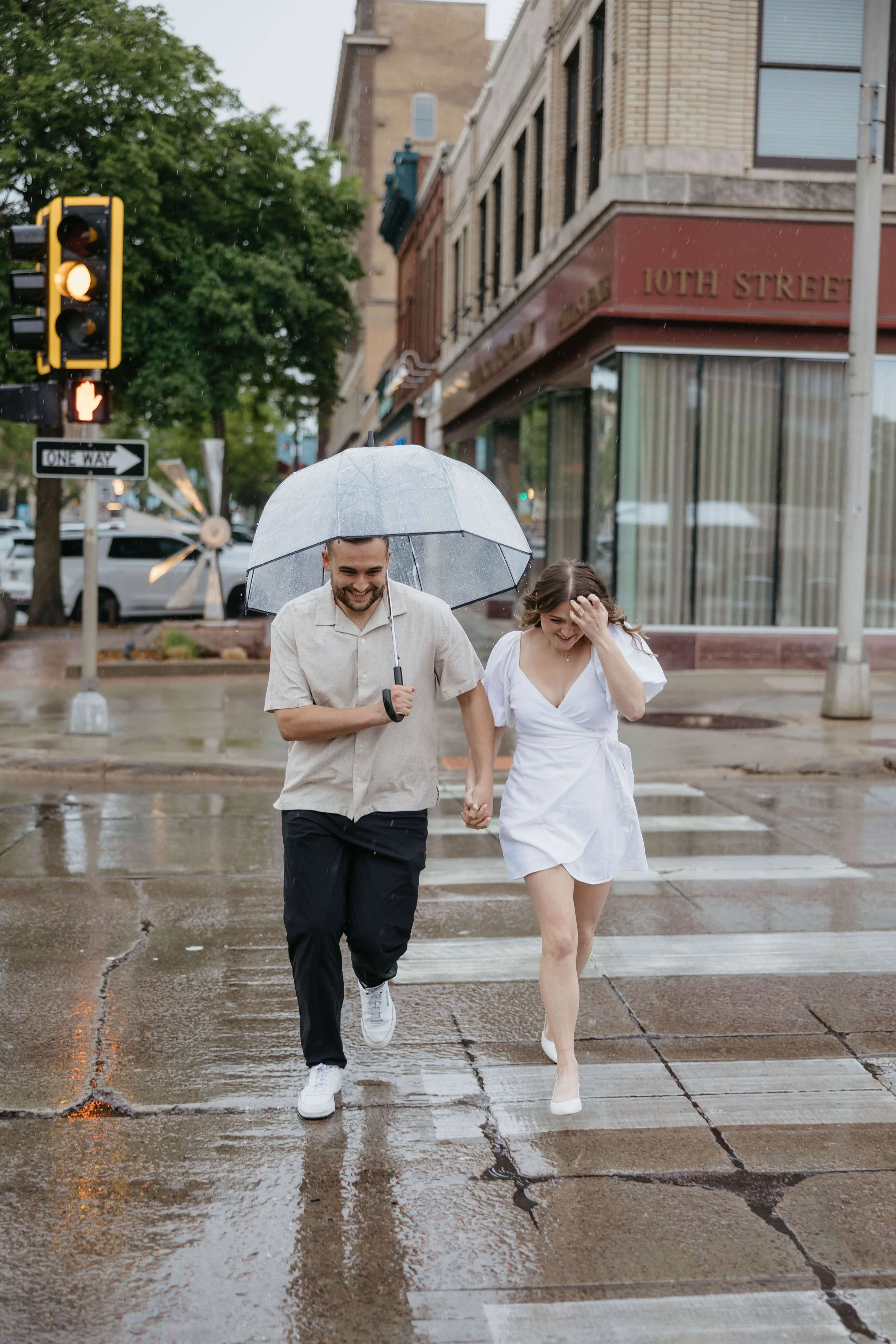 Couple caught in the rain during downtown Sioux Falls engagement session photographed by Jenna Heckel.