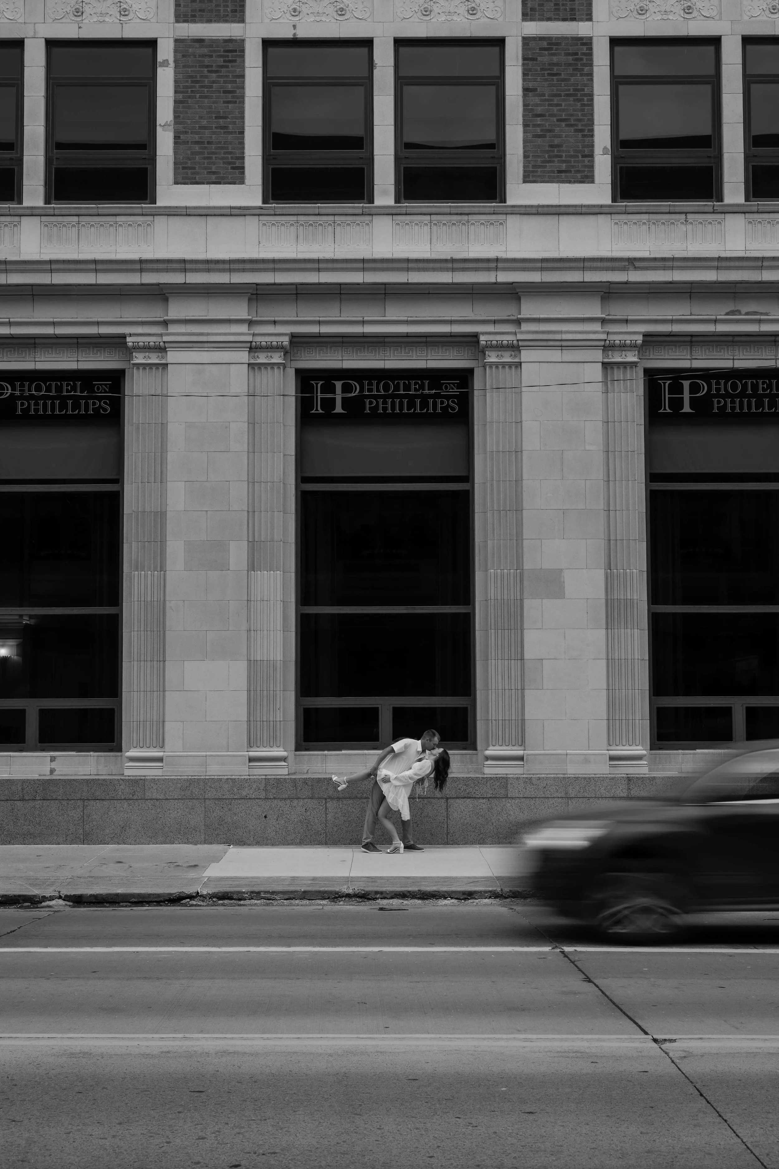 Engaged couple kissing in downtown Sioux Falls outside Hotel on Phillips.