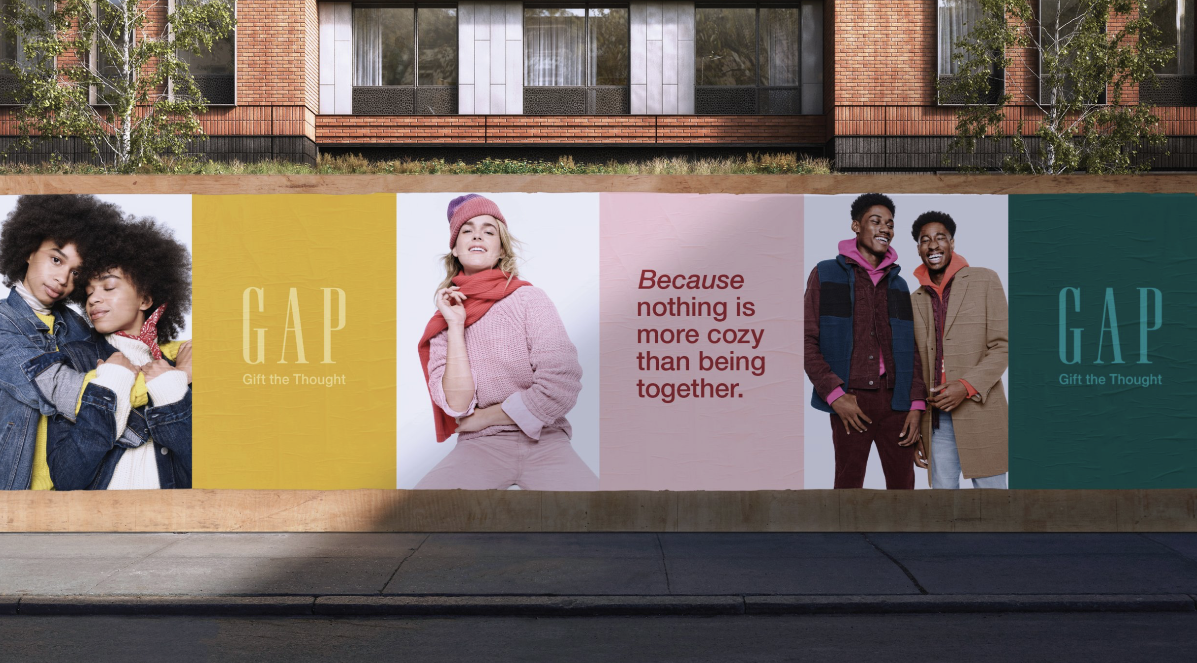 A large outdoor advertisement for GAP featuring diverse models and the slogan, 'Because nothing is more cozy than being together.' The ad promotes gifting the thoughtful experience of being cozy together.