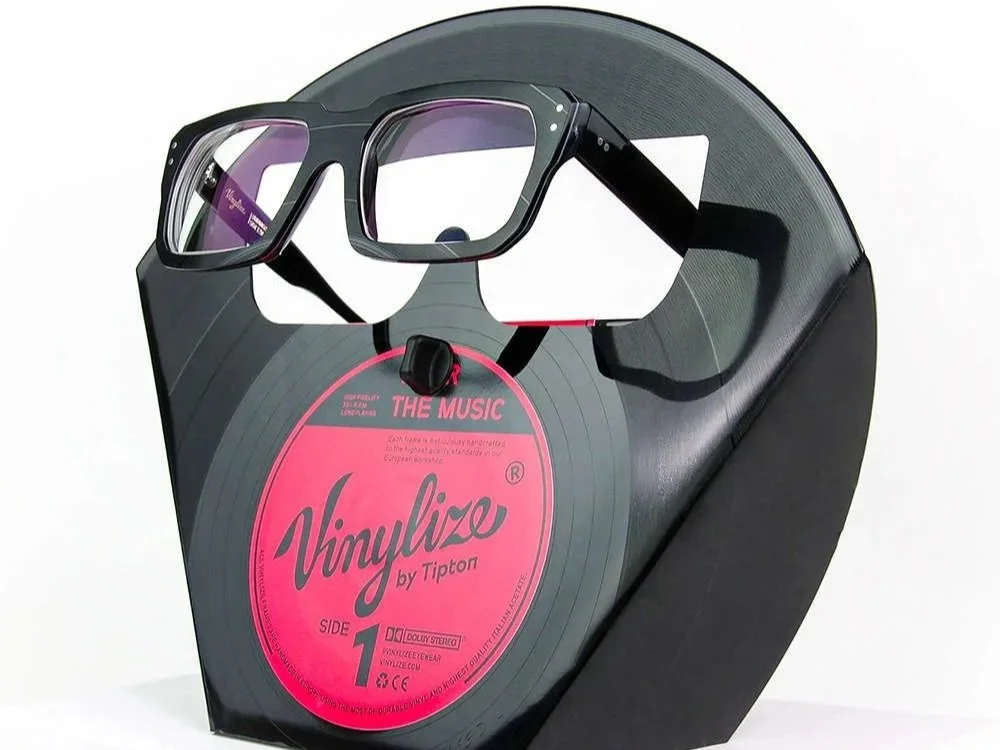 Pair of sunglasses with dark frames and tinted lenses on a black surface.