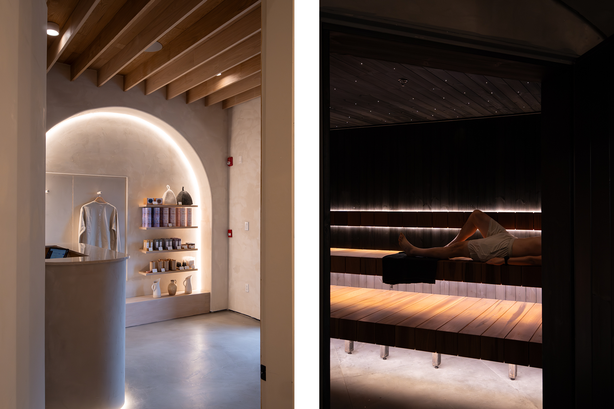 Interior of a spa or wellness center featuring a small shop area on the left with shelves holding skincare products, clothing, and decorative vases, and a relaxation room on the right with wooden benches and a person lying down, illuminated by warm, dark lighting.