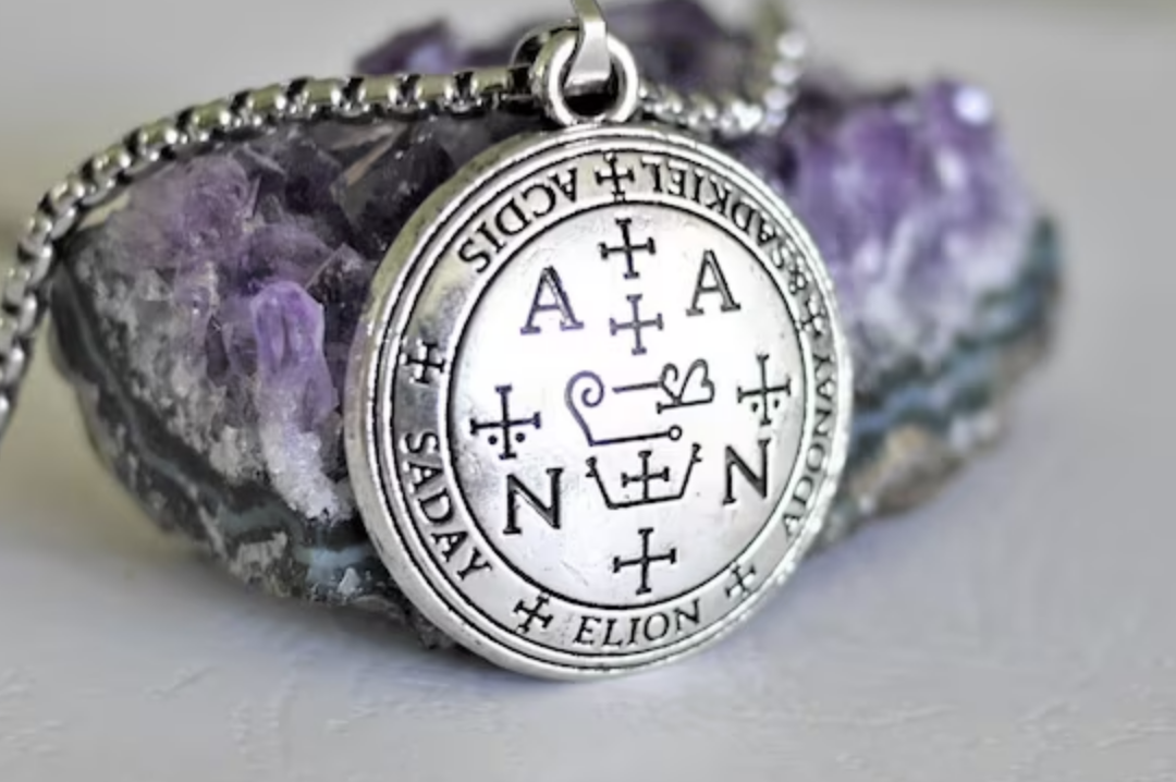 Silver necklace with a round pendant featuring runes and symbols, resting on purple and white mineral rocks.