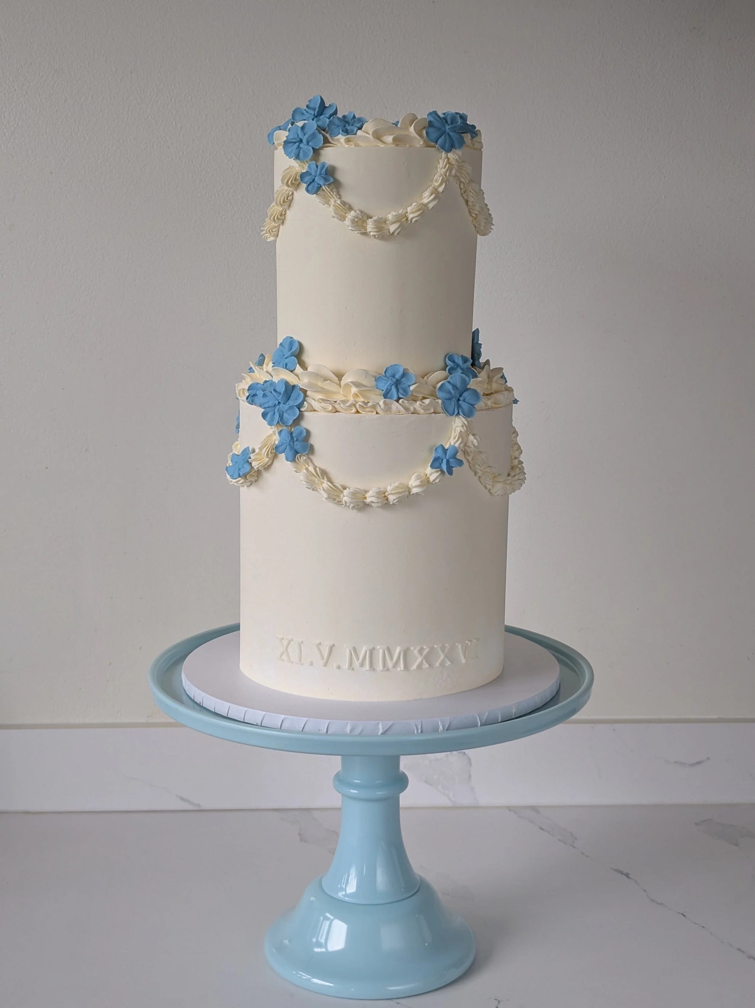 Vintage style wedding cake with blue flowers and roman numerals