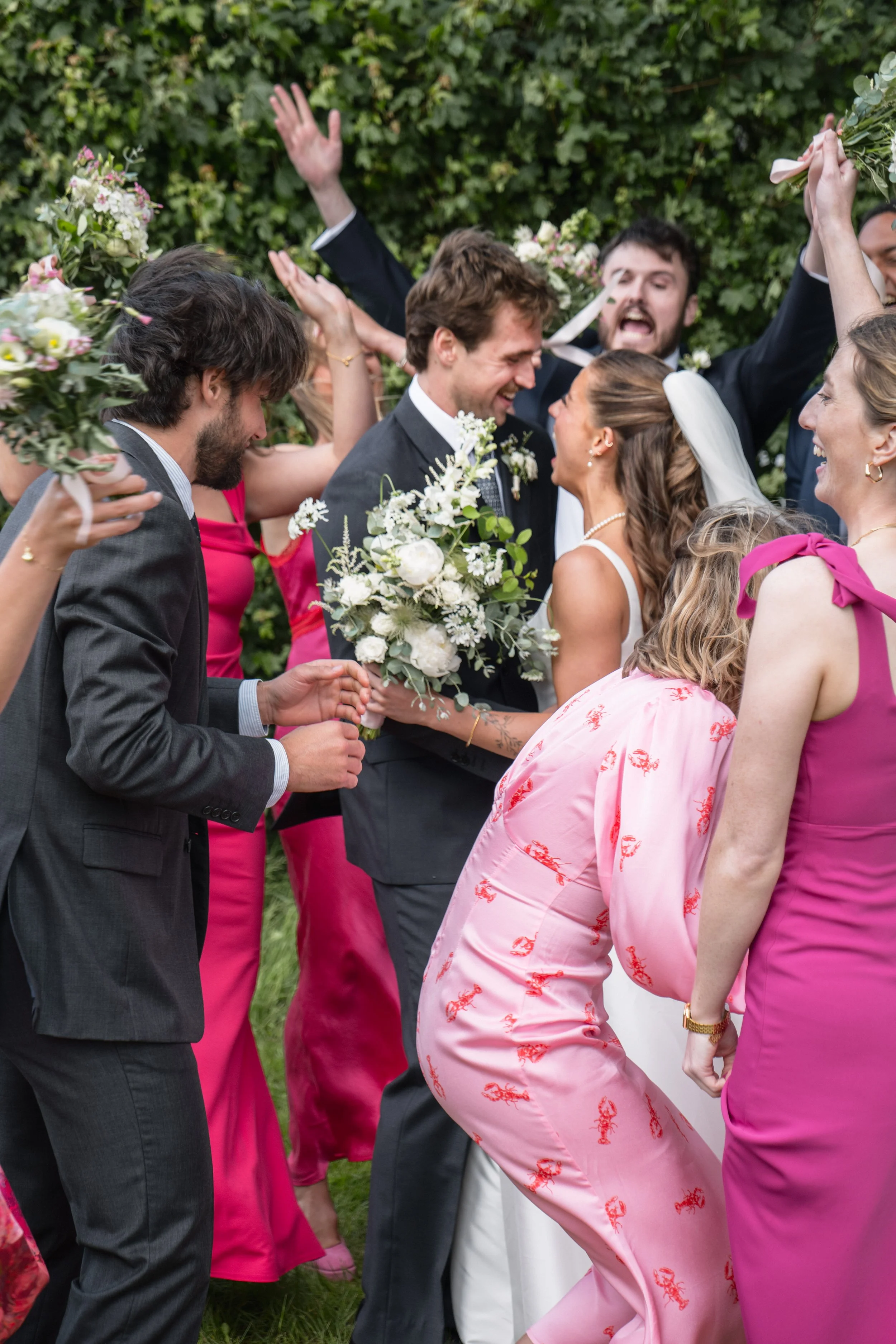 People celebrating at a wedding, exchanging smiles and holding bouquets outdoors