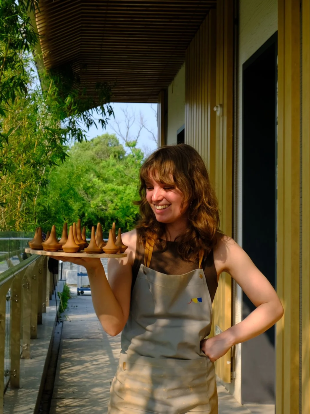 Claudia standing with a wheel-thrown ceramic pot during a residency in Jingdezhen, China.