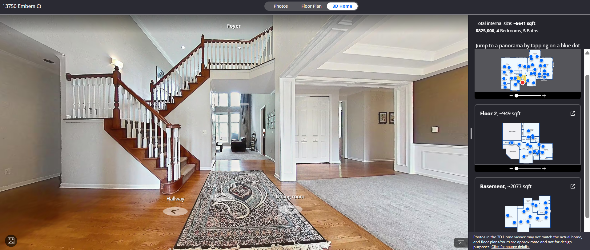 Interior view of a spacious home foyer and entryway with a wooden staircase, carpet runner, and entry hall leading to a living room with large windows and seating area.