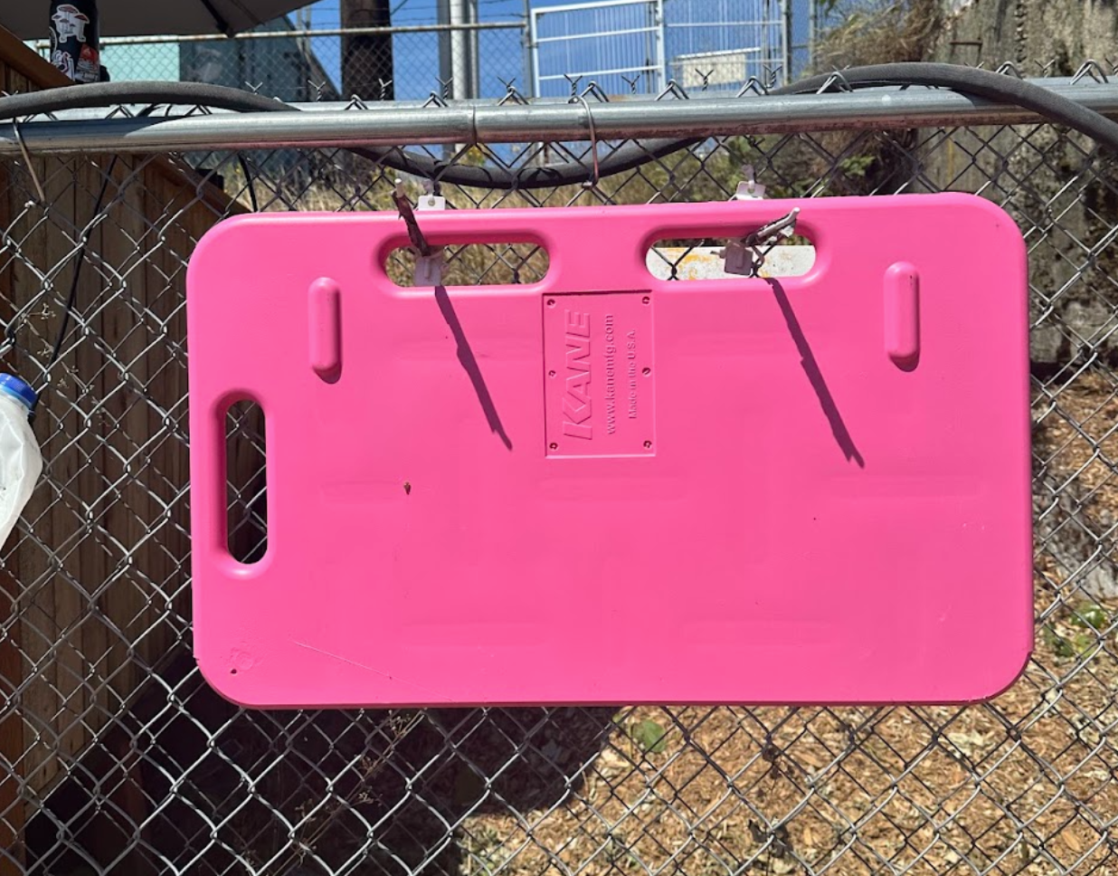 A pink pig board hanging on a chain-link fence