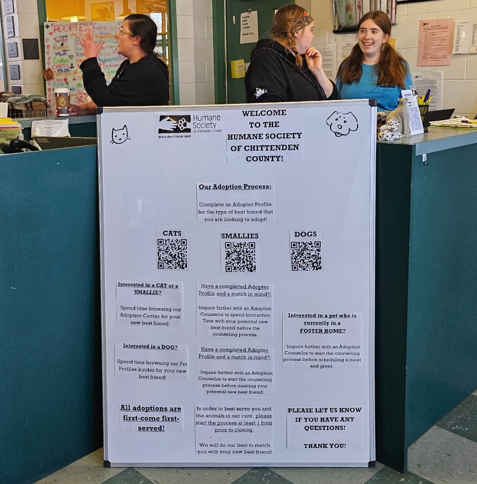 A large introductory sign sits in the entryway of an animal shelter's lobby, featuring information about adopting animals in care.
