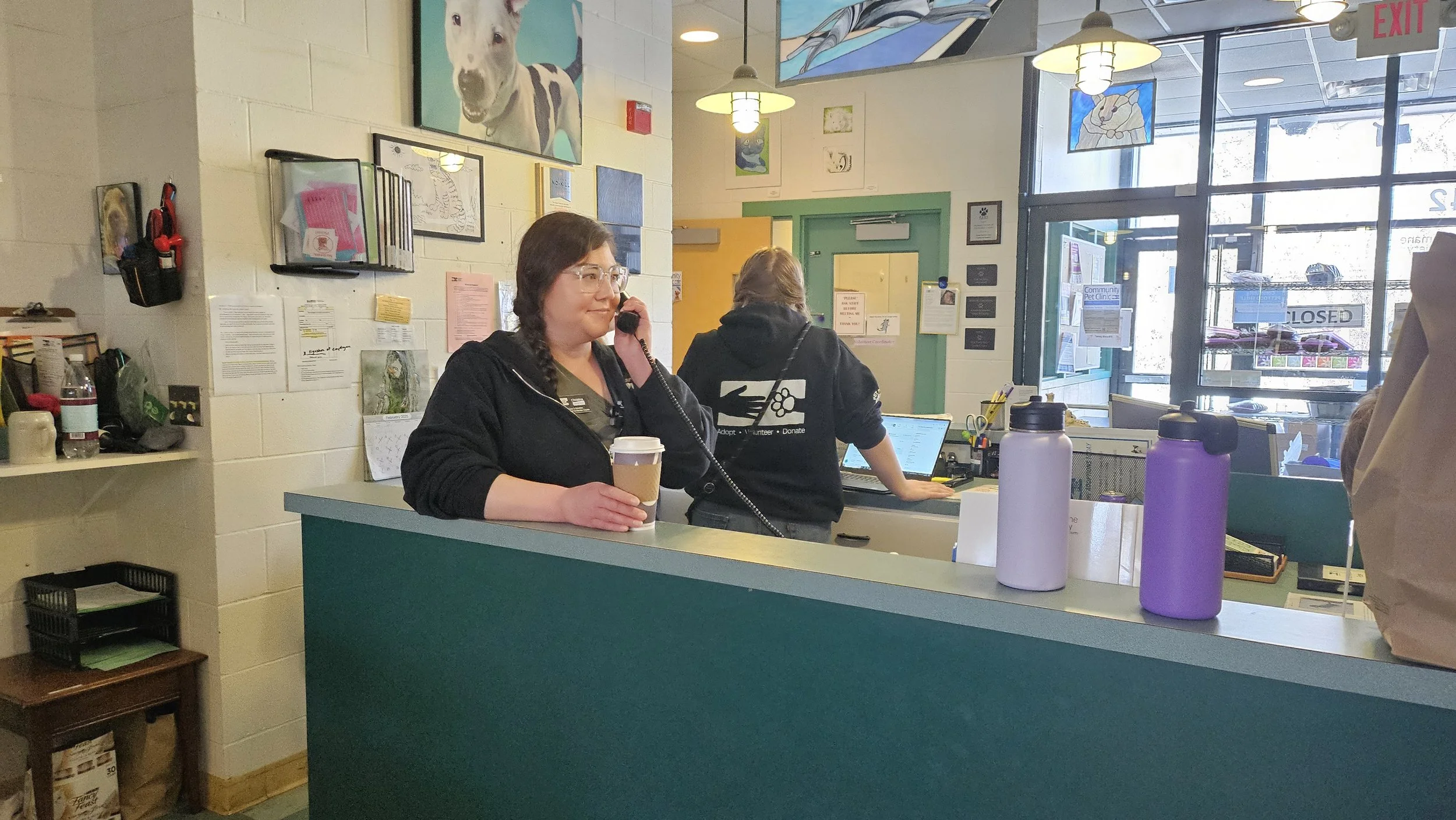A shelter staff member sits with a coffee talking on a phone.