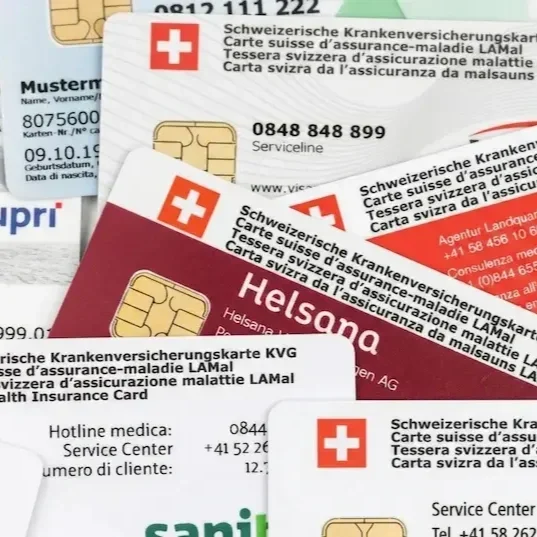 Mehrere Schweizer Krankenversicherungskarten, insbesondere aus Helsinki, in verschiedenen Farben und Designs, mit Swiss-Cross-Logo und Kontaktinformationen.