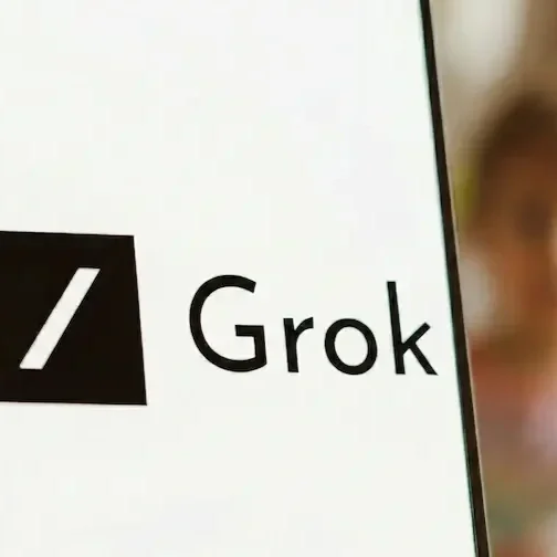 Nahaufnahme eines Schildes mit dem Logo von dem KI Modell 'Grok' und einem verschwommenen Kind.