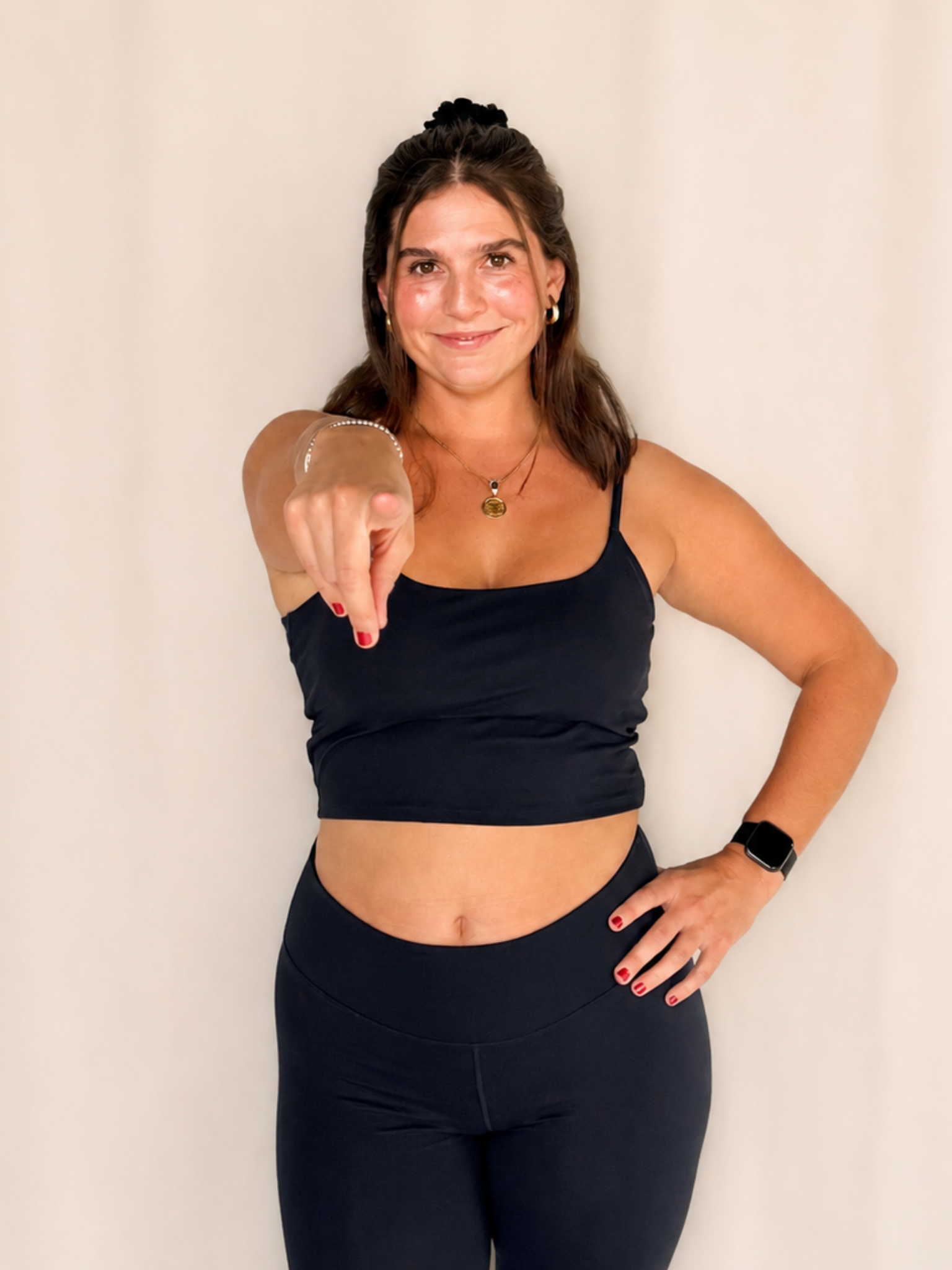 Woman in a navy two piece pointing at the camera while smiling.