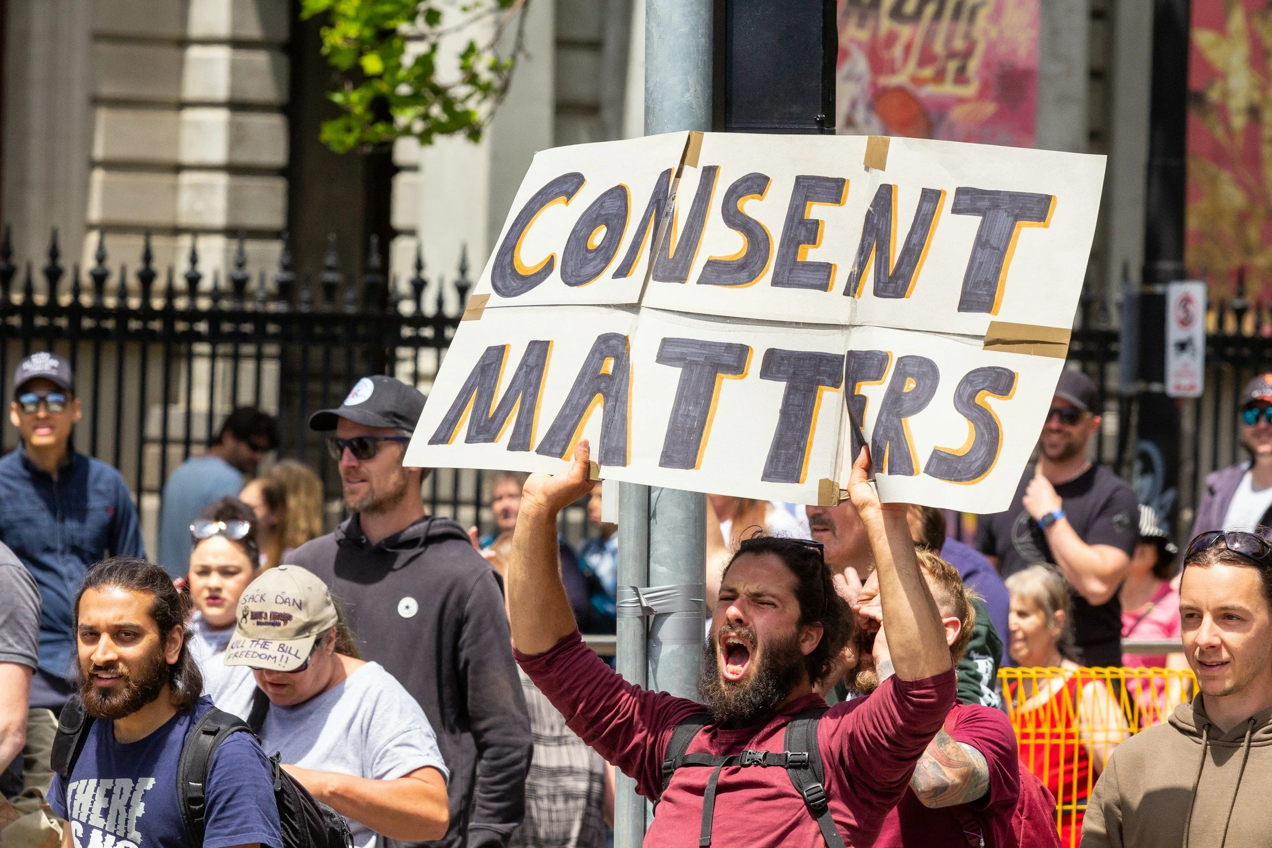 Man in crowd holding banner saying "Consent Matters"
