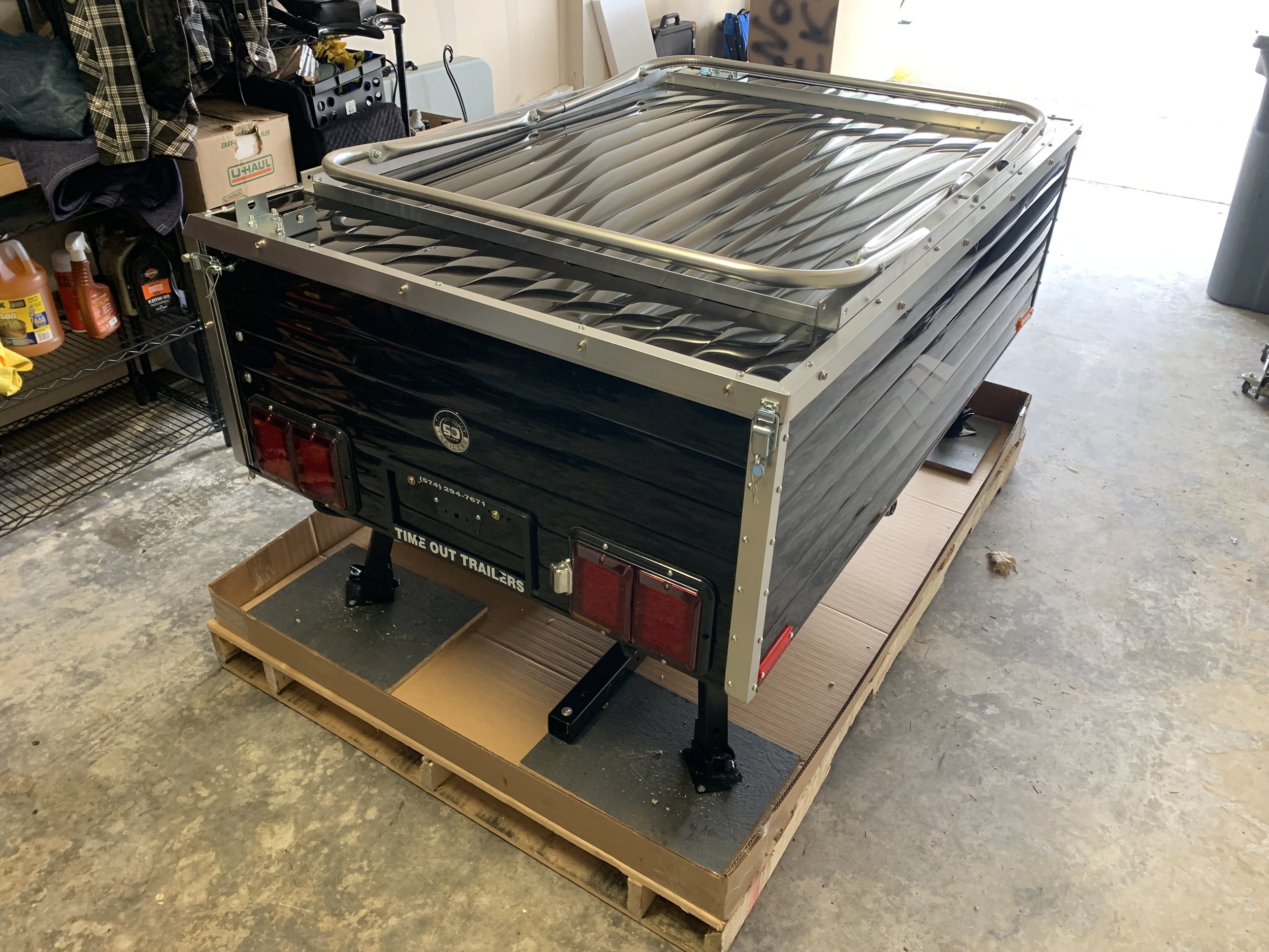 Time Out Deluxe motorcycle camper trailer freshly  uncrated on delivery pallet before assembly with  jack stand visible and no tires installed yet