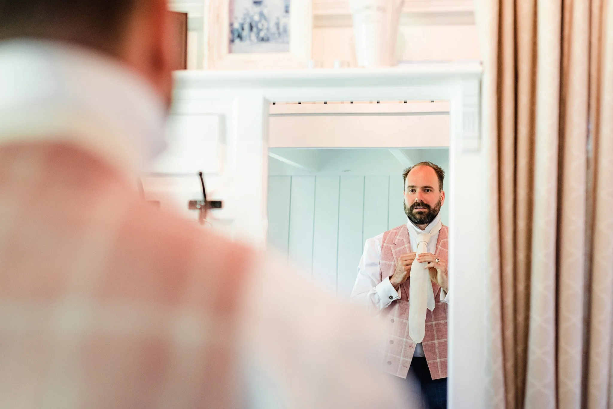 Groom getting tie ready in the mirror