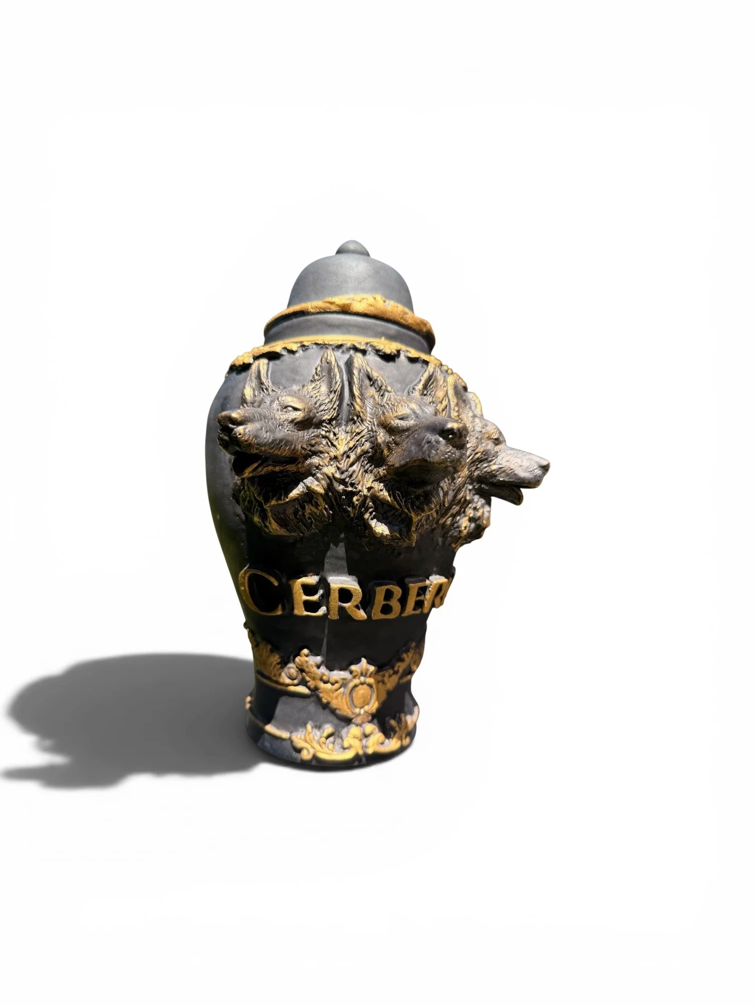 Decorative award or trophy featuring a black and gold design with a crest of three wolves and the word "CERBER" at the base, casting a shadow on a white background.