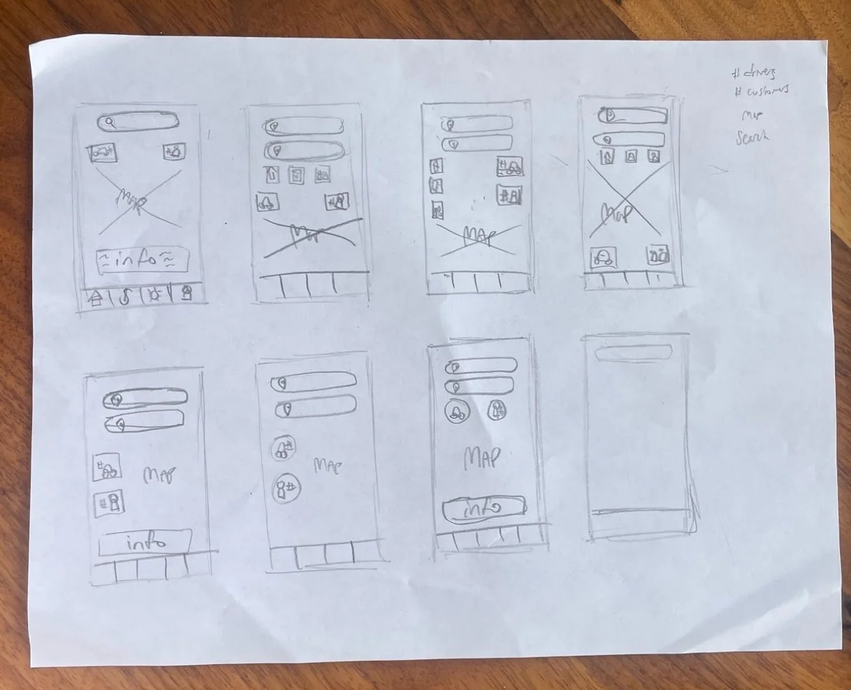 Hand-drawn sketches of mobile app interface designs on a sheet of paper showing several layouts with search bars, icons, and maps.