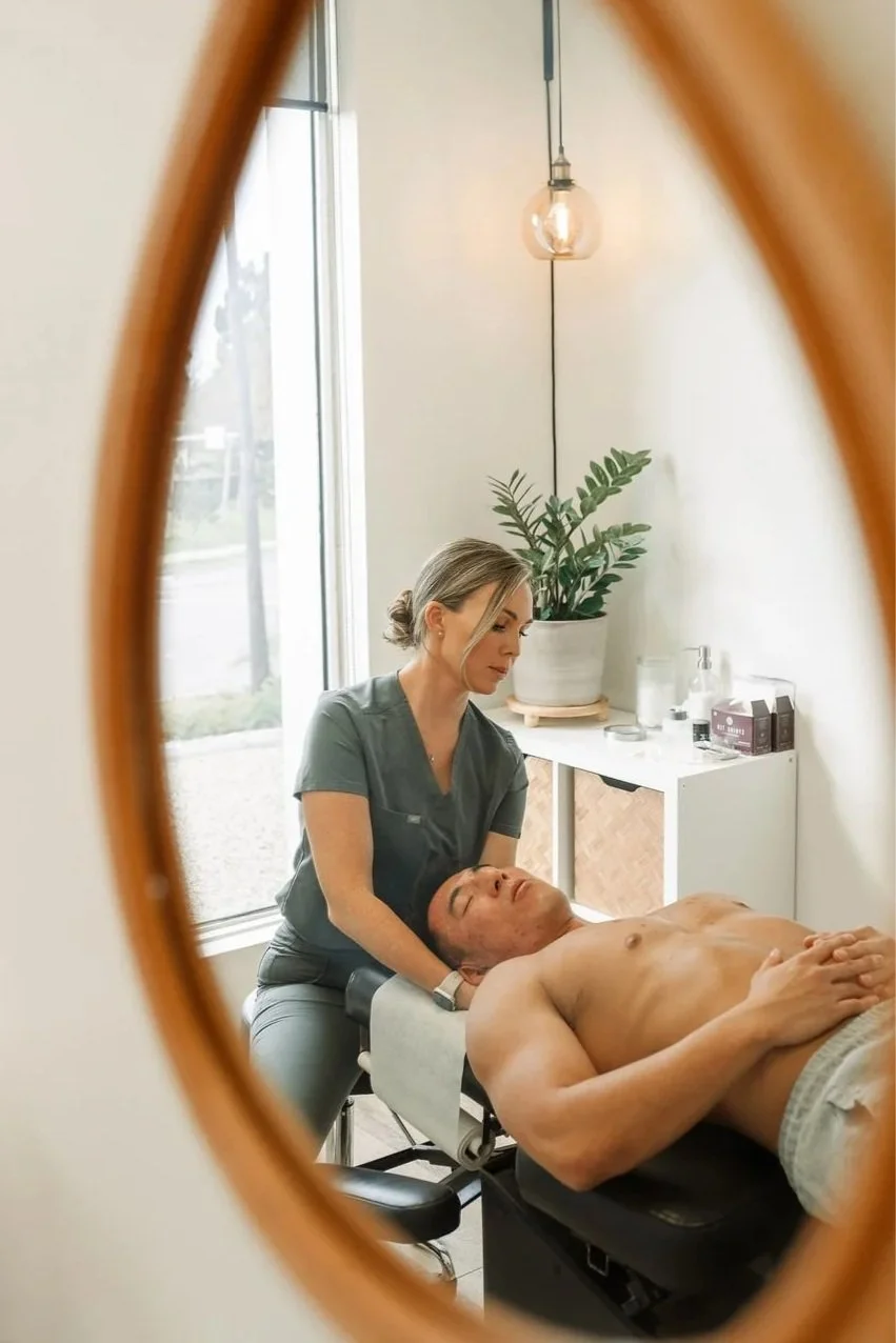 A woman in scrubs giving treatment for neck pain to a man
