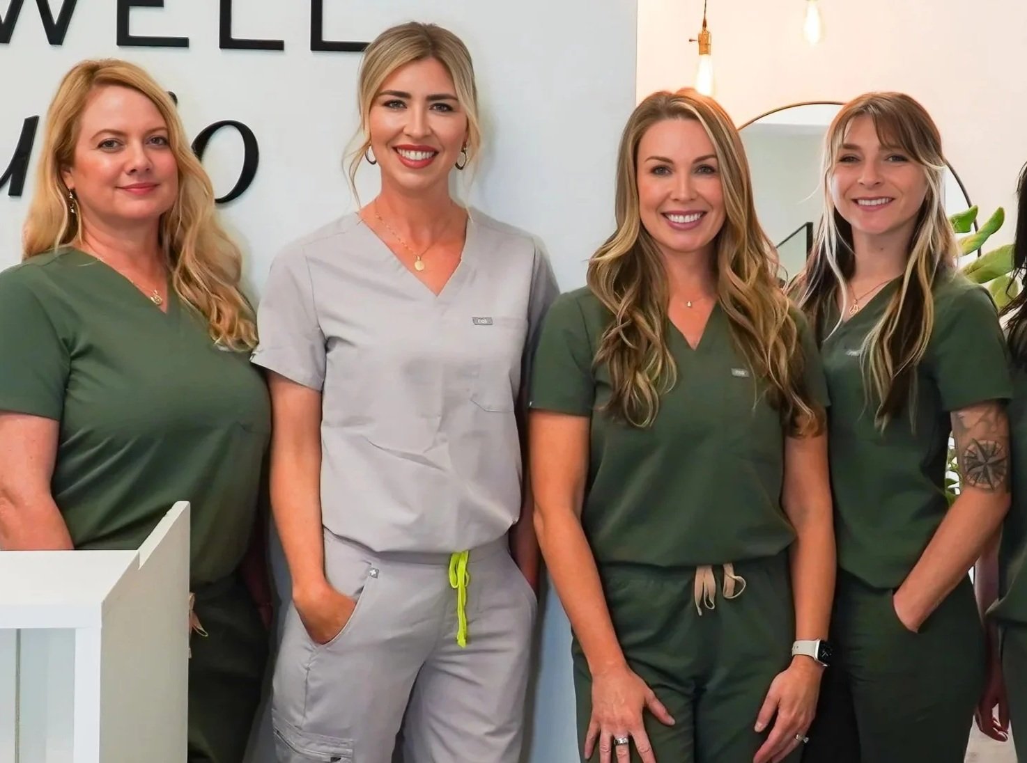 4 women standing in scrubs smiling at oc well studio