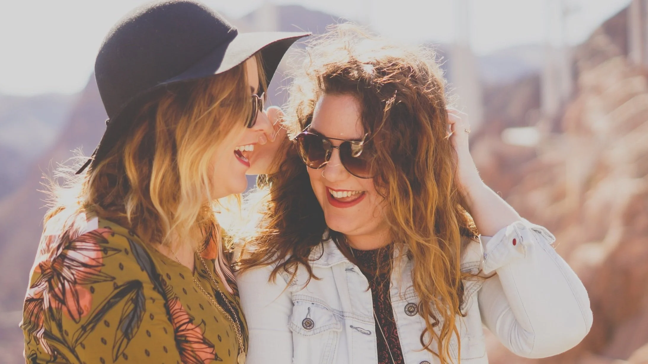 Two white women lean toward one another and laugh during couples therapy.