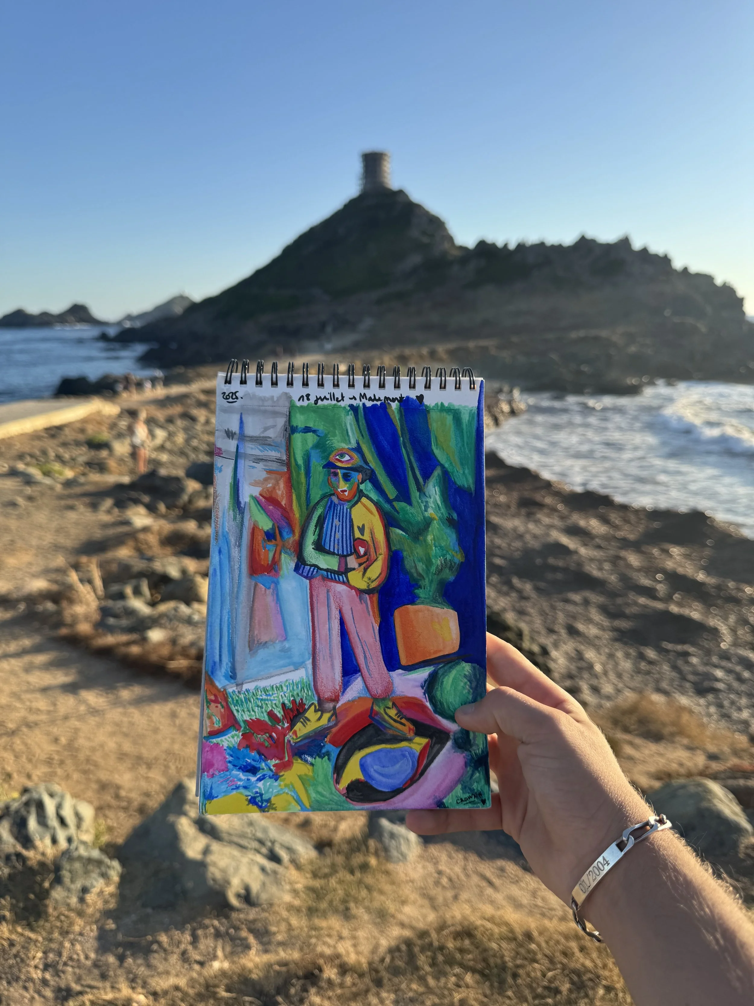Œuvre contemporaine colorée de Crown* présentée dans la main de l’artiste au bord de la mer