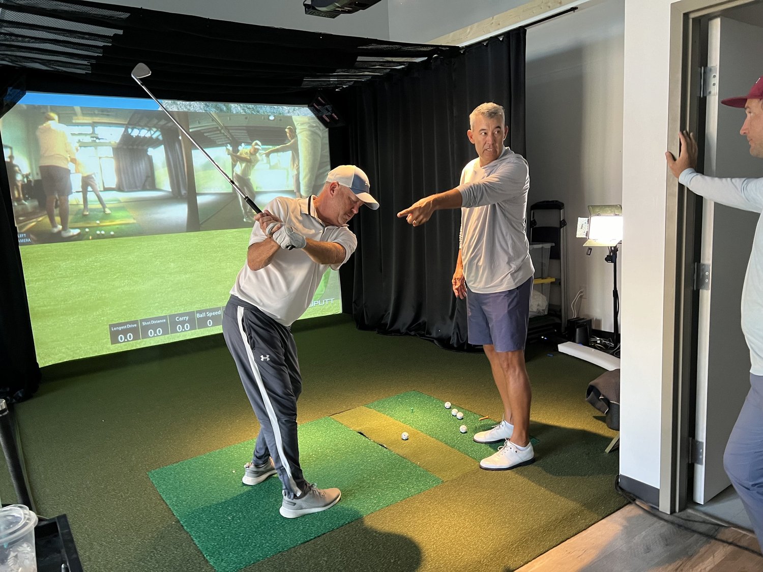 Steve Dahlby coaching a golfer in an indoor simulator bay