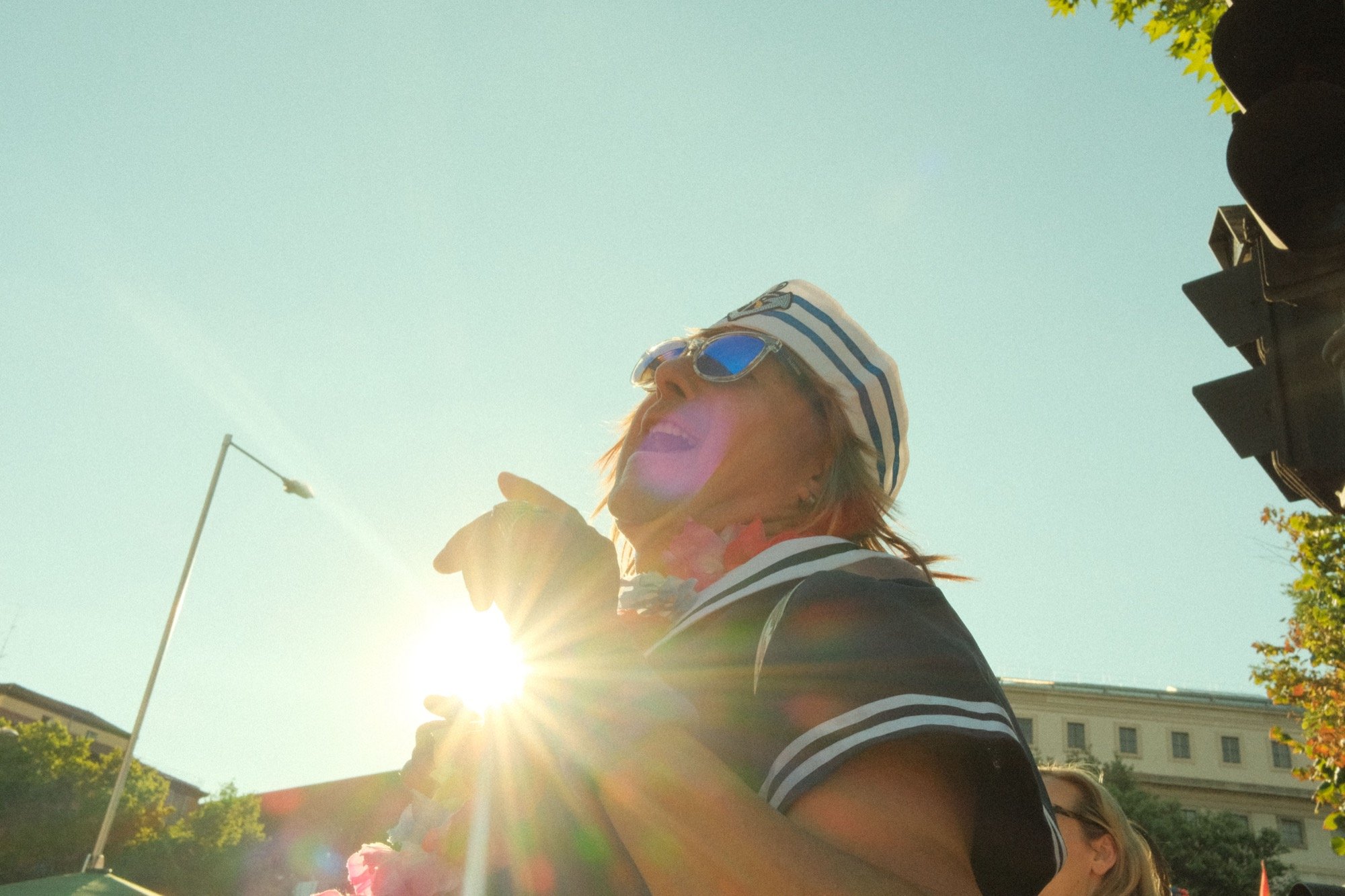 A man in a sailor outfit joyfully dancing with the sunlight behind him at Madrid Pride 2024