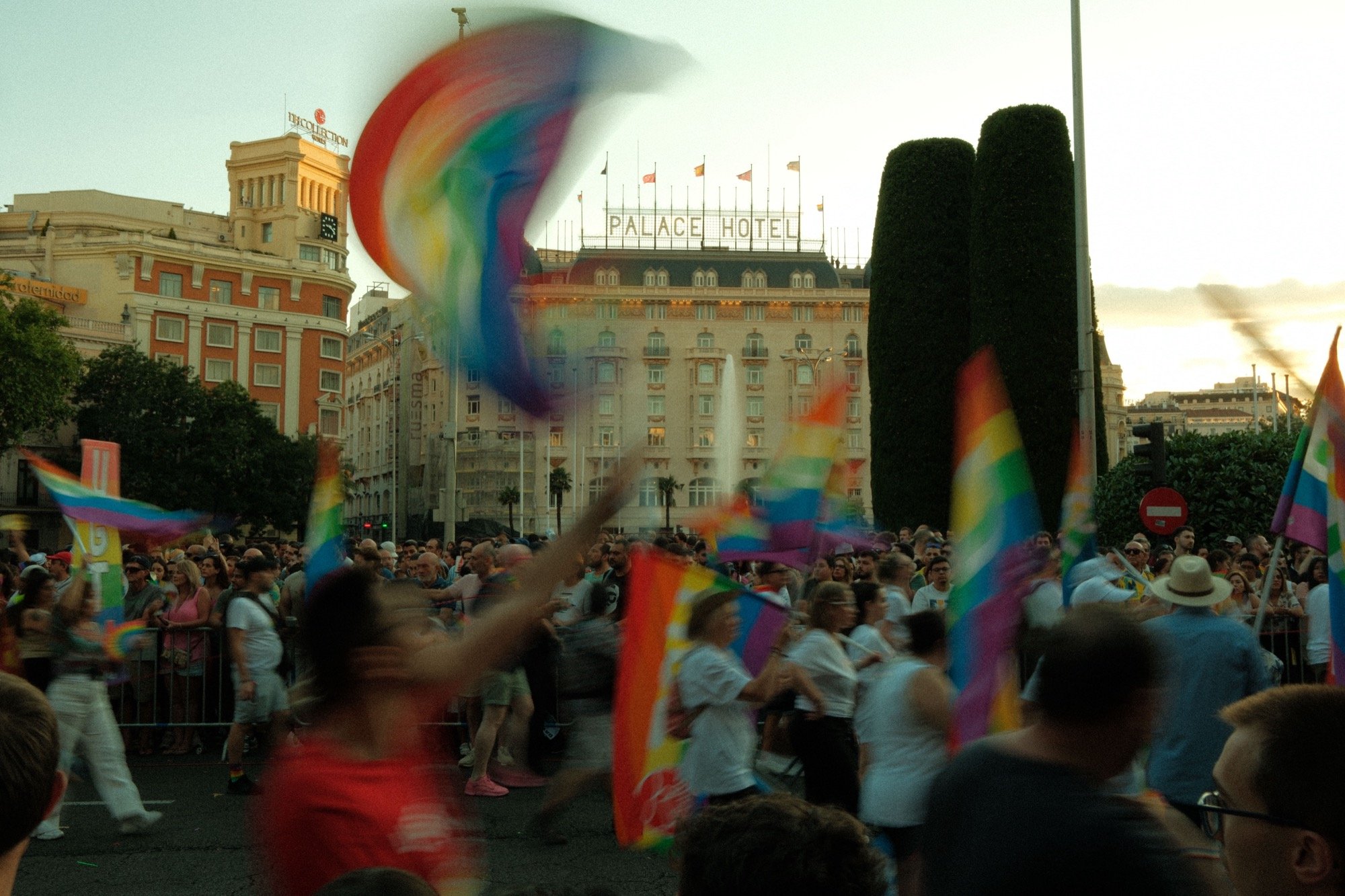 Rainbow Pride flags waving in front of the historic Palace Hotel as crowds gather for Madrid Pride 2024