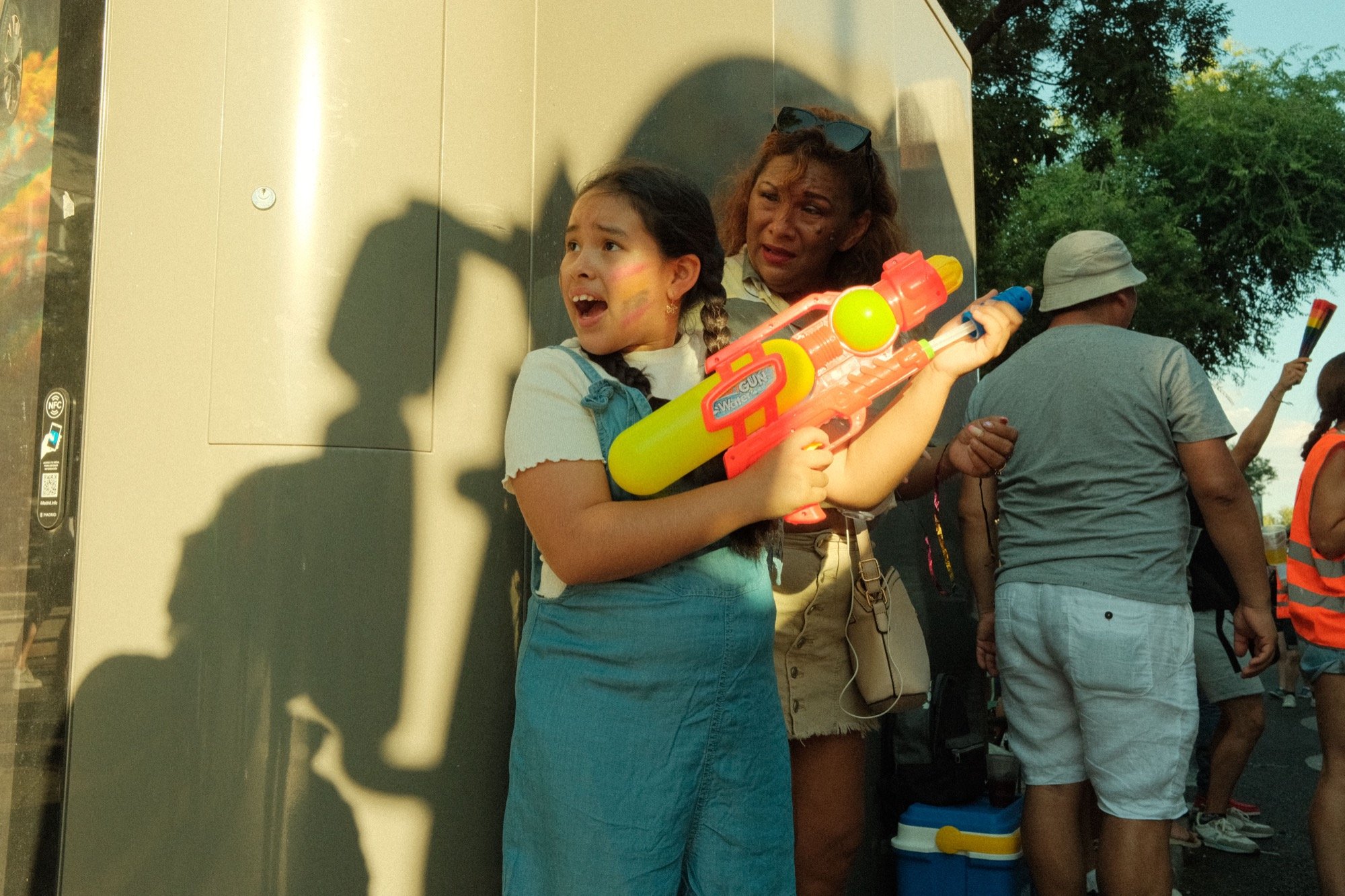 Reactions of a young girl holding a water gun as she playfully engages with the crowd during Madrid Pride 2024