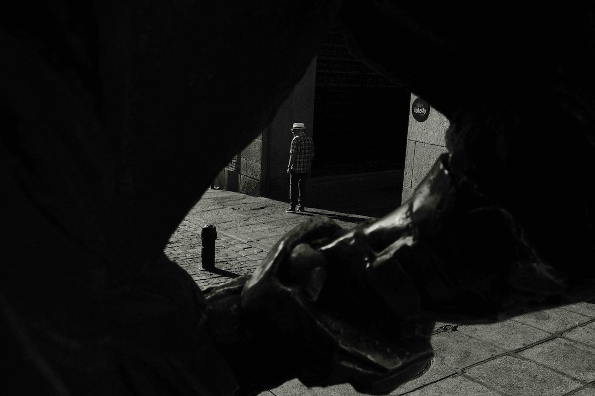 Close-up view through a statue silhouette of a man wearing a hat in Toledo’s old town