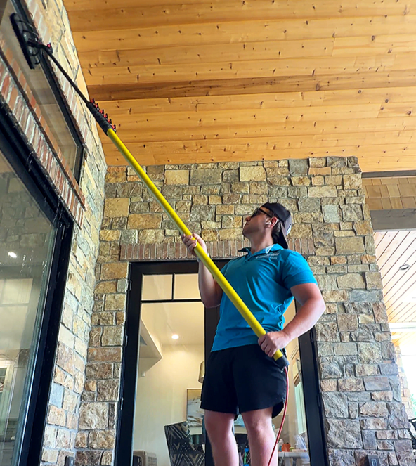 ClearView Cleanings Technician using pure-water pole to wash second-story windows on a Highlands Ranch home, leaving a streak-free finish