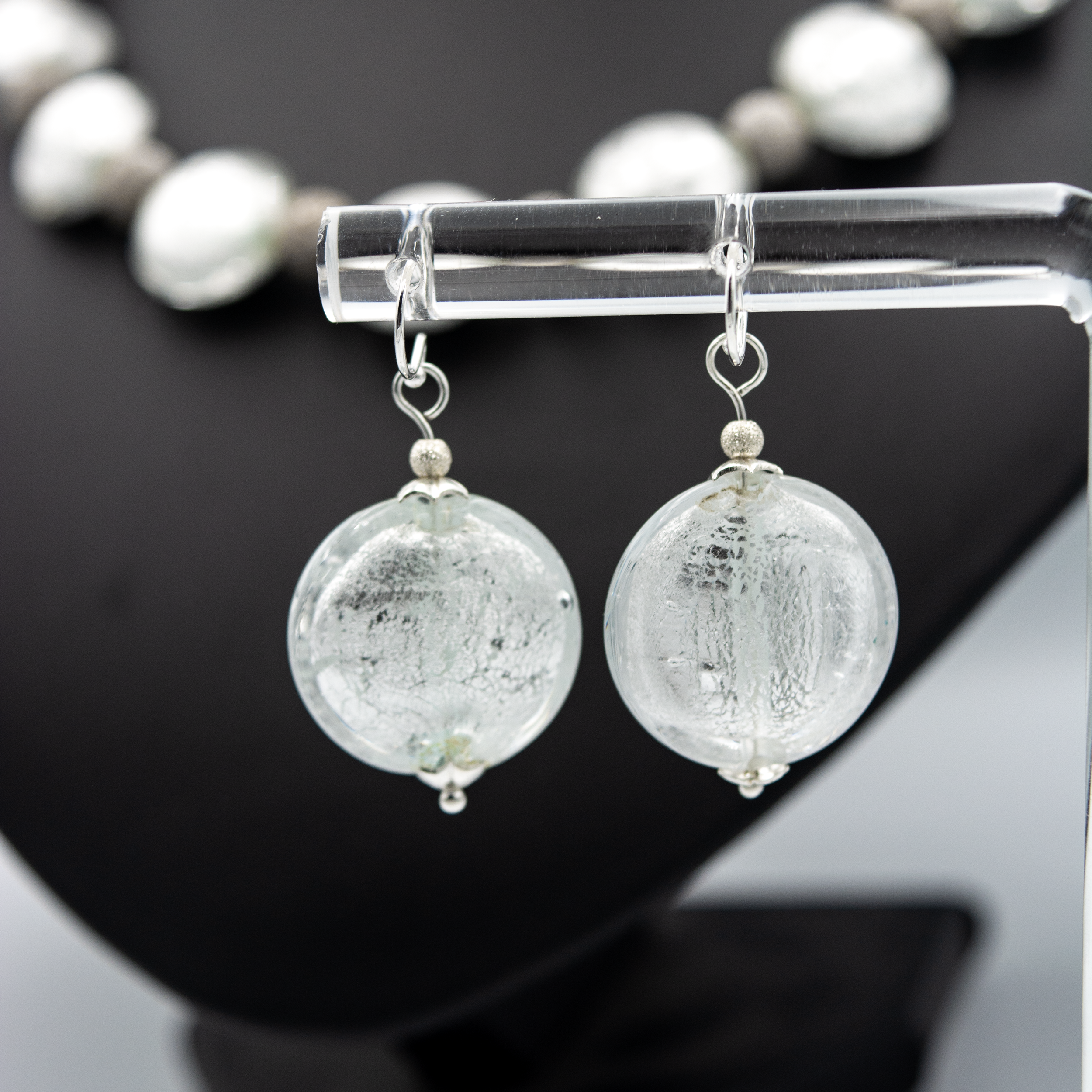 Detalle de pendientes Argento hechos a mano en vidrio de Murano con reflejos plateados y plata de ley.