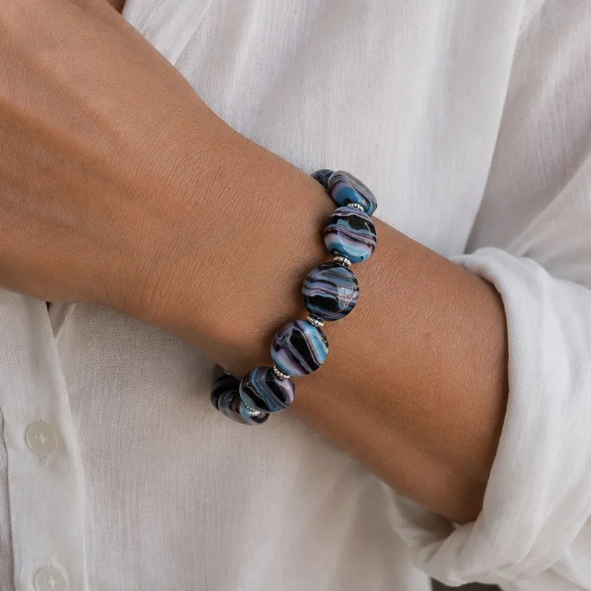 Mujer llevando pulsera Iris de vidrio de Murano artesanal y plata de ley con reflejos cambiantes y elegantes.