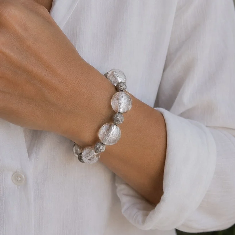 Mujer llevando pulsera Argento de vidrio de Murano artesanal y plata de ley con elegantes destellos plateados.
