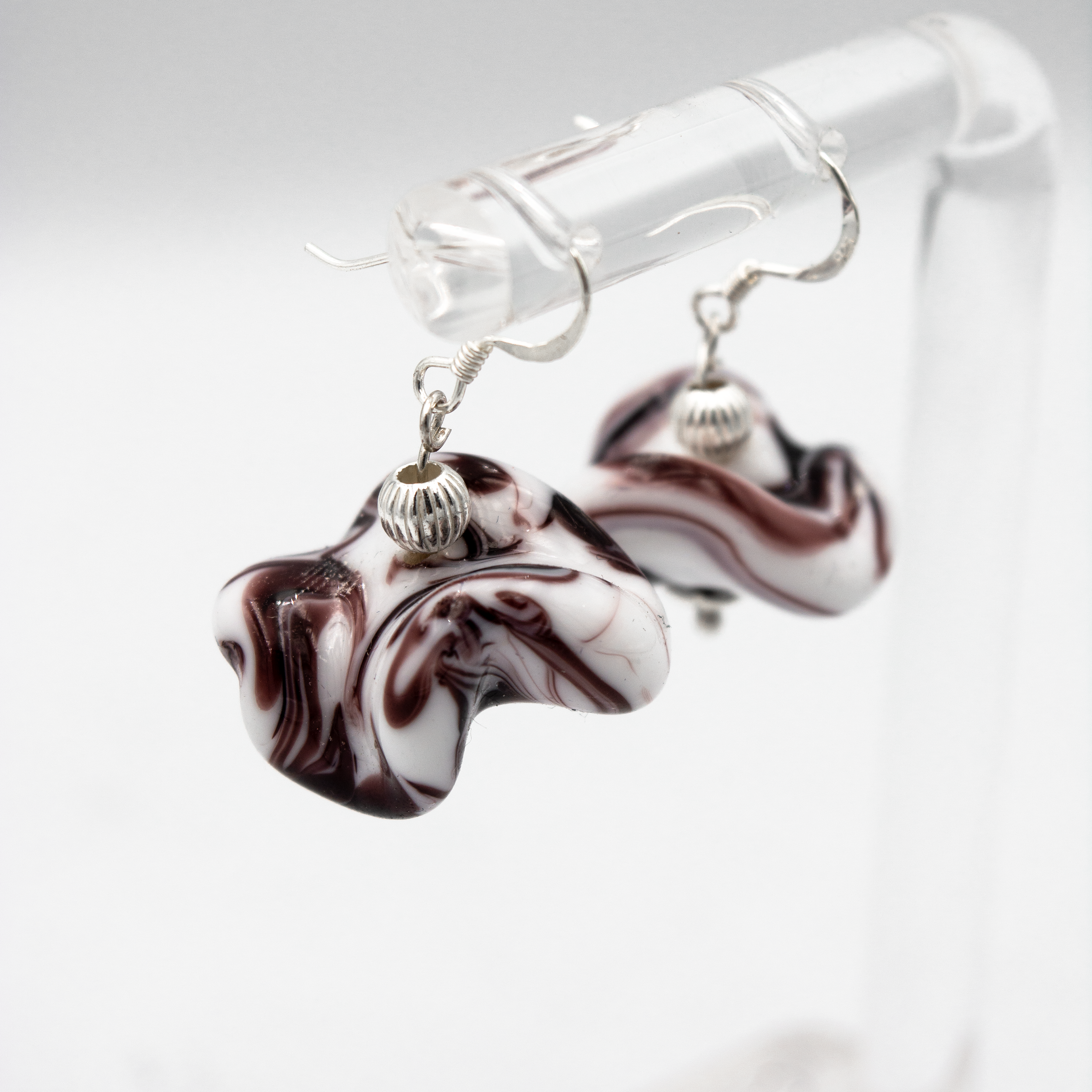 Detalle de pendientes Onde Blanco hechos a mano en vidrio de Murano con reflejos nacarados y plata de ley.
