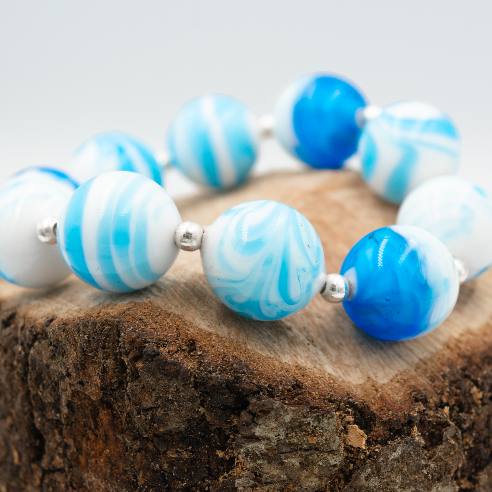 Detalle de pulsera Mar hecha a mano en vidrio de Murano con reflejos oceánicos y plata de ley.