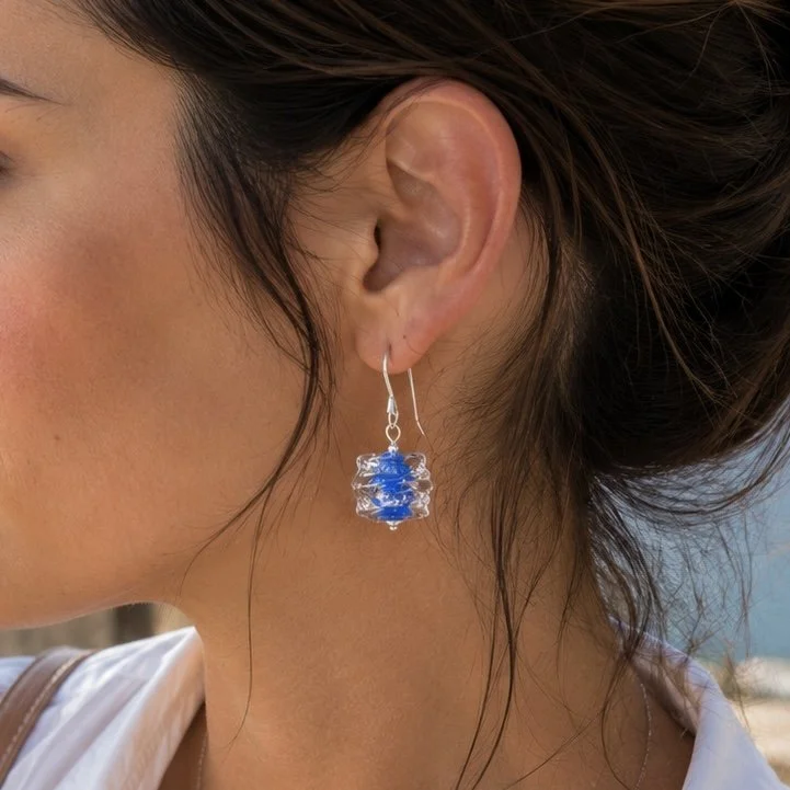 Mujer llevando pendientes Luar Azul Pastel de vidrio de Murano artesanal y plata de ley con delicados reflejos luminosos.