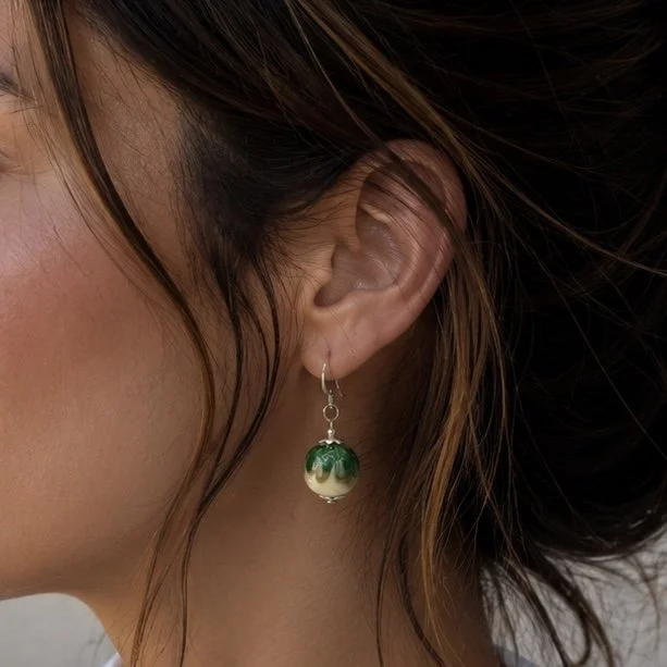 Mujer llevando pendientes Esmeralda de vidrio de Murano artesanal y plata de ley con luminosos reflejos verdes.